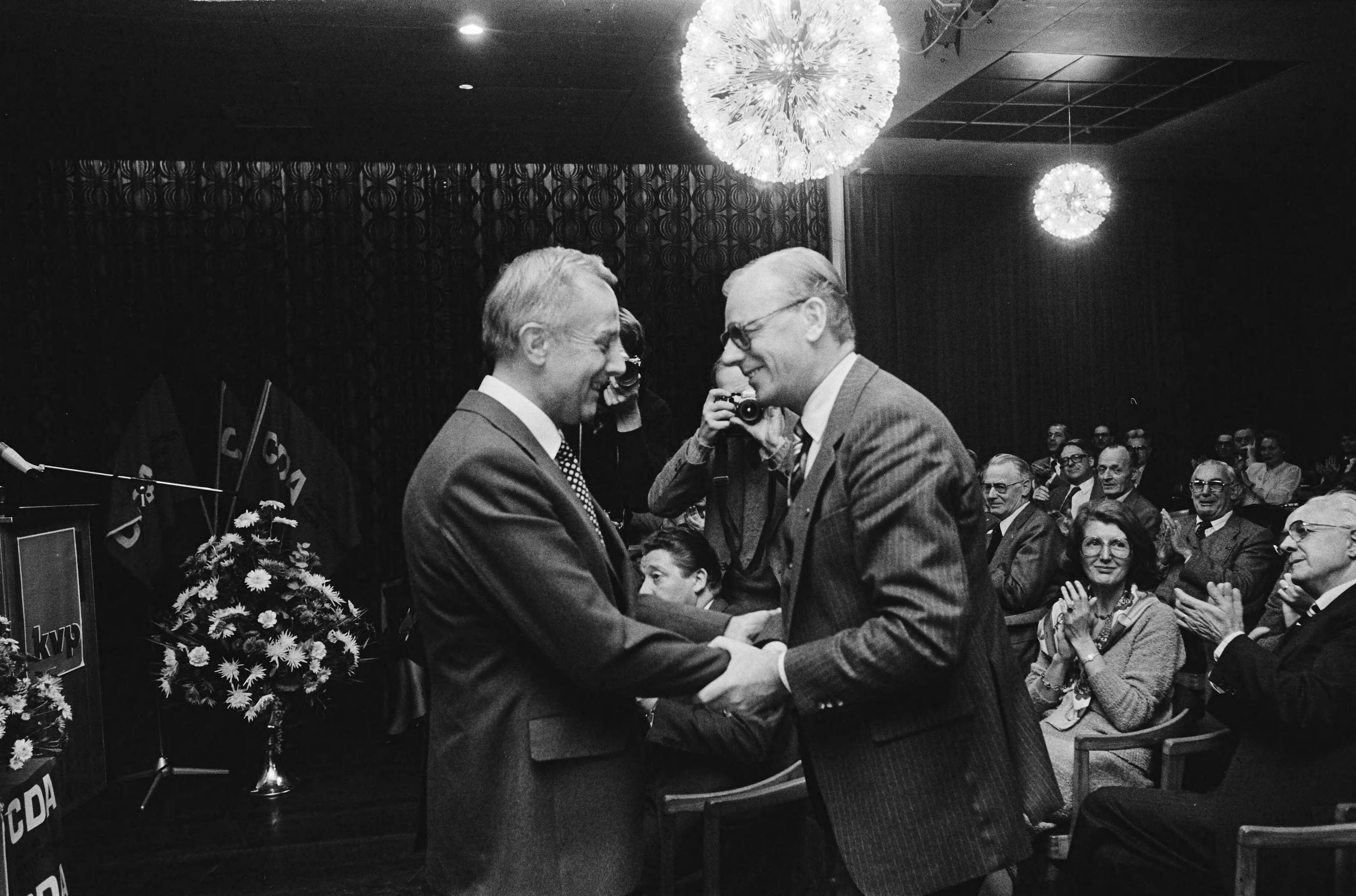 KVP partijraad in Hilversum — Oud KVP voorzitter Wim Vergeer (r) wenst zijn opvolger Piet van Zeil succes — Foto: Bogaerts, Rob / Anefo. Licentie: Set B: Rechtenvrij / Publiek Domein. Bron: Nationaal Archief. http://hdl.handle.net/10648/acd4829e-d0b4-102d-bcf8-003048976d84