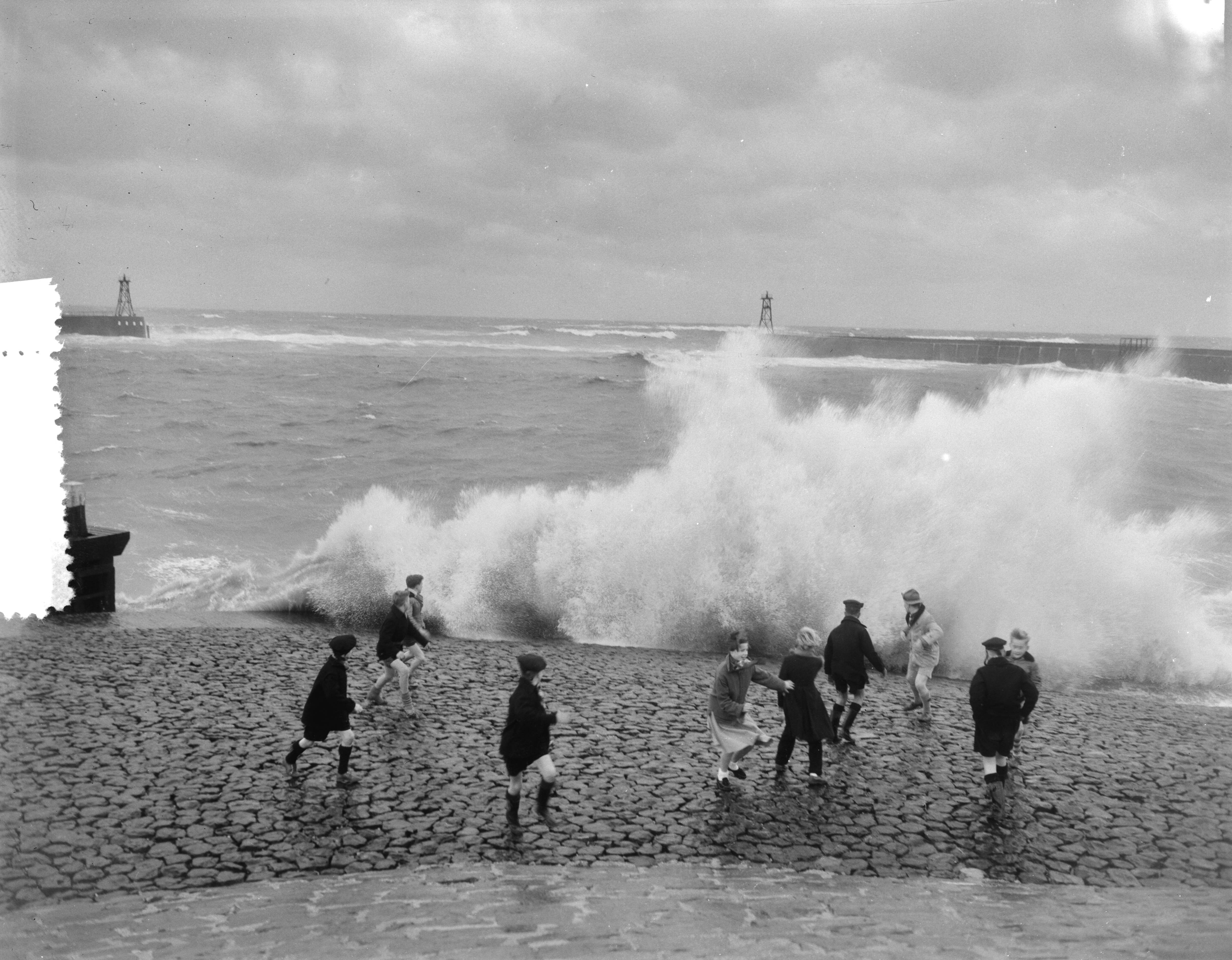 Fotocollectie Anefo — Westerstorm aan de kust van Scheveningen. Overslaande golven, kinderen rennen weg — Foto: Pot, Harry / Anefo. Licentie: Set B: Rechtenvrij / Publiek Domein. Bron: Nationaal Archief. http://hdl.handle.net/10648/a940fdb0-d0b4-102d-bcf8-003048976d84