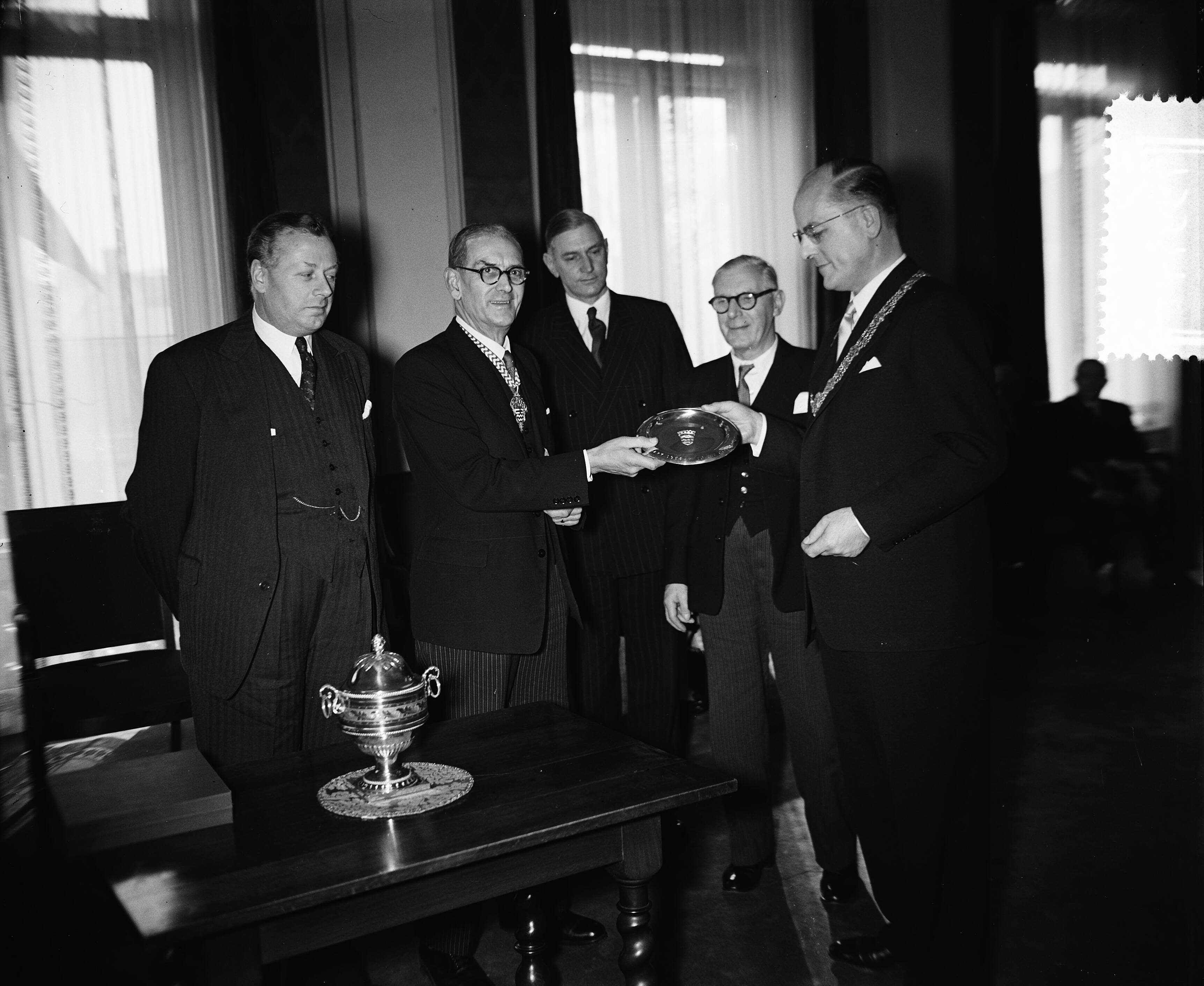 Fotocollectie Anefo — Gemeentebestuur van Londen in Den Haag. Chairman mr. Norman Prichard (links in het midden) met burgemeester mr. W.F.A. Schokking (rechts) — Foto: Rossem, Wim van / Anefo. Licentie: Set B: Rechtenvrij / Publiek Domein. Bron: Nationaal Archief. http://hdl.handle.net/10648/a94338fa-d0b4-102d-bcf8-003048976d84