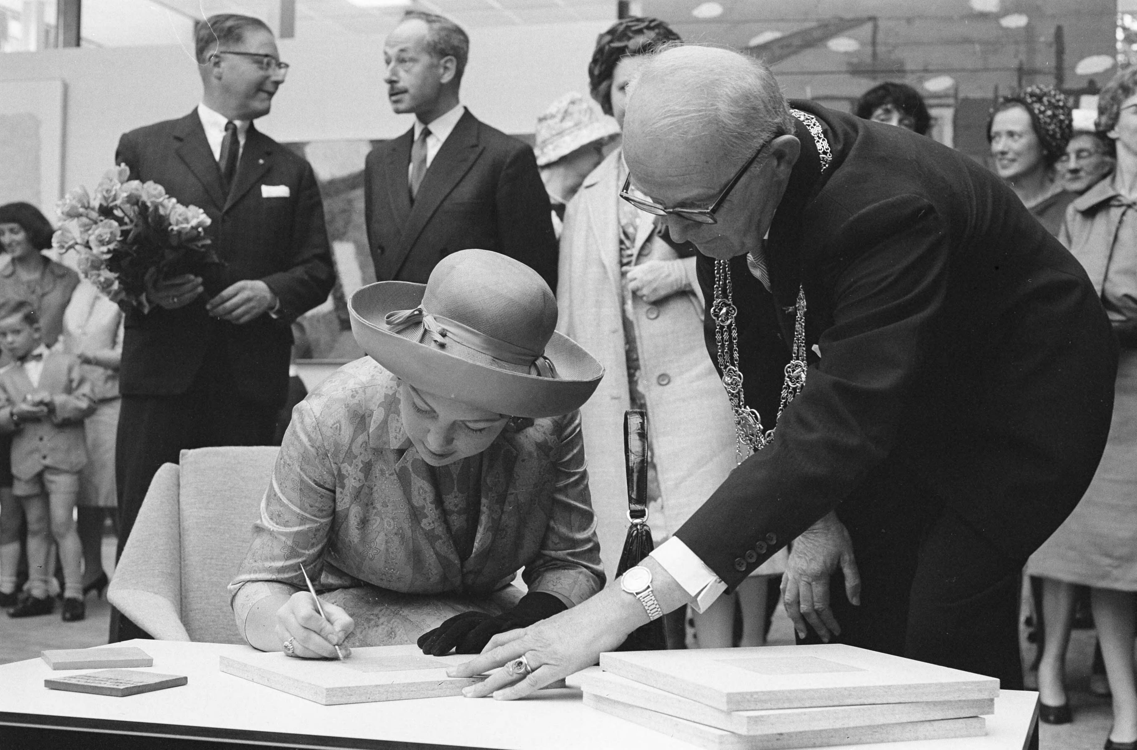 Fotocollectie Anefo — Prinses Beatrix opende nieuwe vleugel van het Haags Gemeentemuseum. De prinses graveerde haar handtekening in de klei van een tegel. Burgemeester Kolfschoten assisteert haar — Foto: Pot, Harry / Anefo. Licentie: Set B: Rechtenvrij / Publiek Domein. Bron: Nationaal Archief. http://hdl.handle.net/10648/aa0f406c-d0b4-102d-bcf8-003048976d84