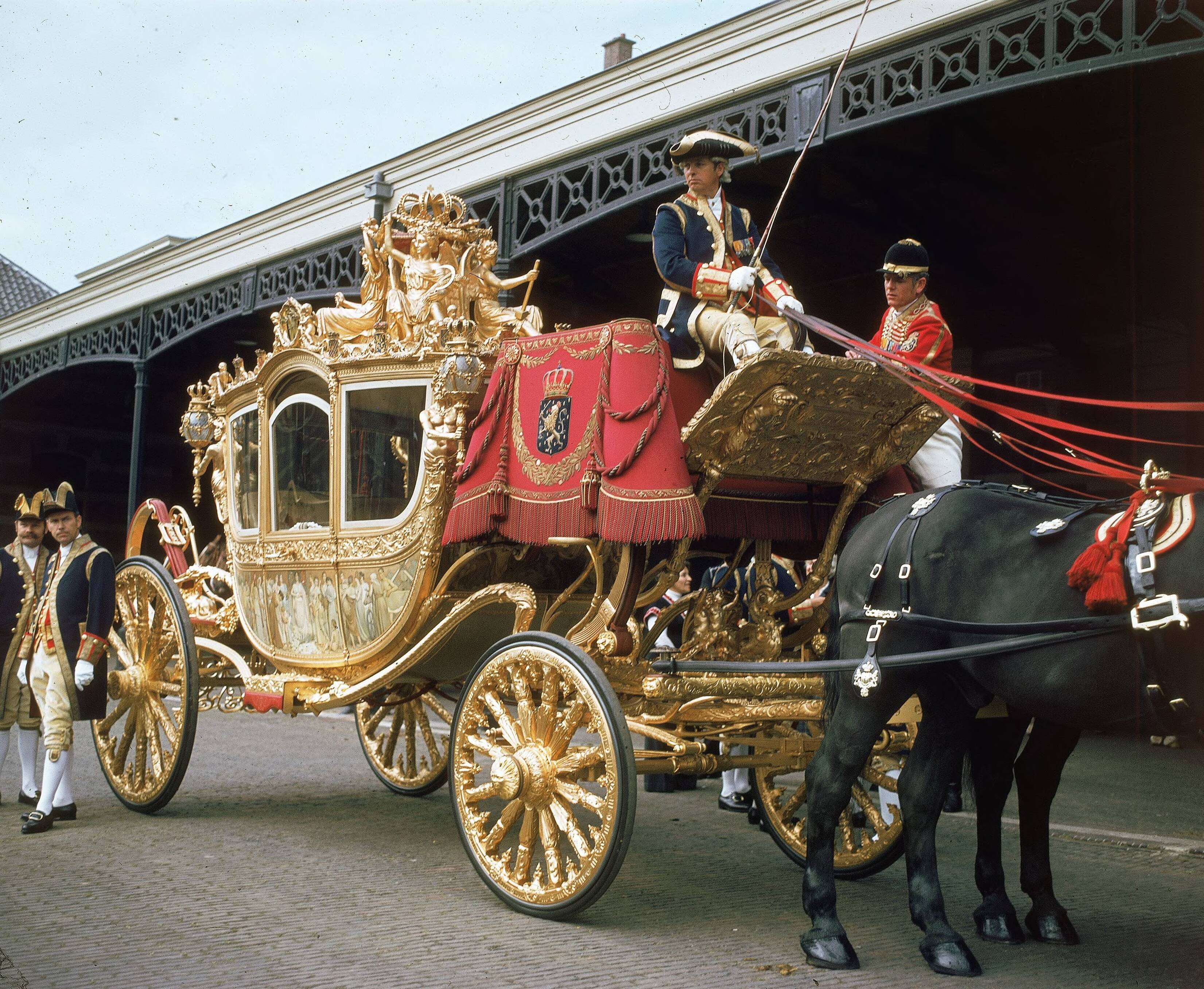 Fotocollectie RVD / Koninklijk Huis — Prinsjesdag - Gouden koets, met koetsier, lakeien, stalpersoneel en paard op de binnenplaats van de koninklijke stallen aan de Noordwal te Den Haag — Foto: Mastenbroek, Cees / RVD. Licentie: Set B: Rechtenvrij / Publiek Domein. Bron: Nationaal Archief. http://hdl.handle.net/10648/afb2764c-d0b4-102d-bcf8-003048976d84
