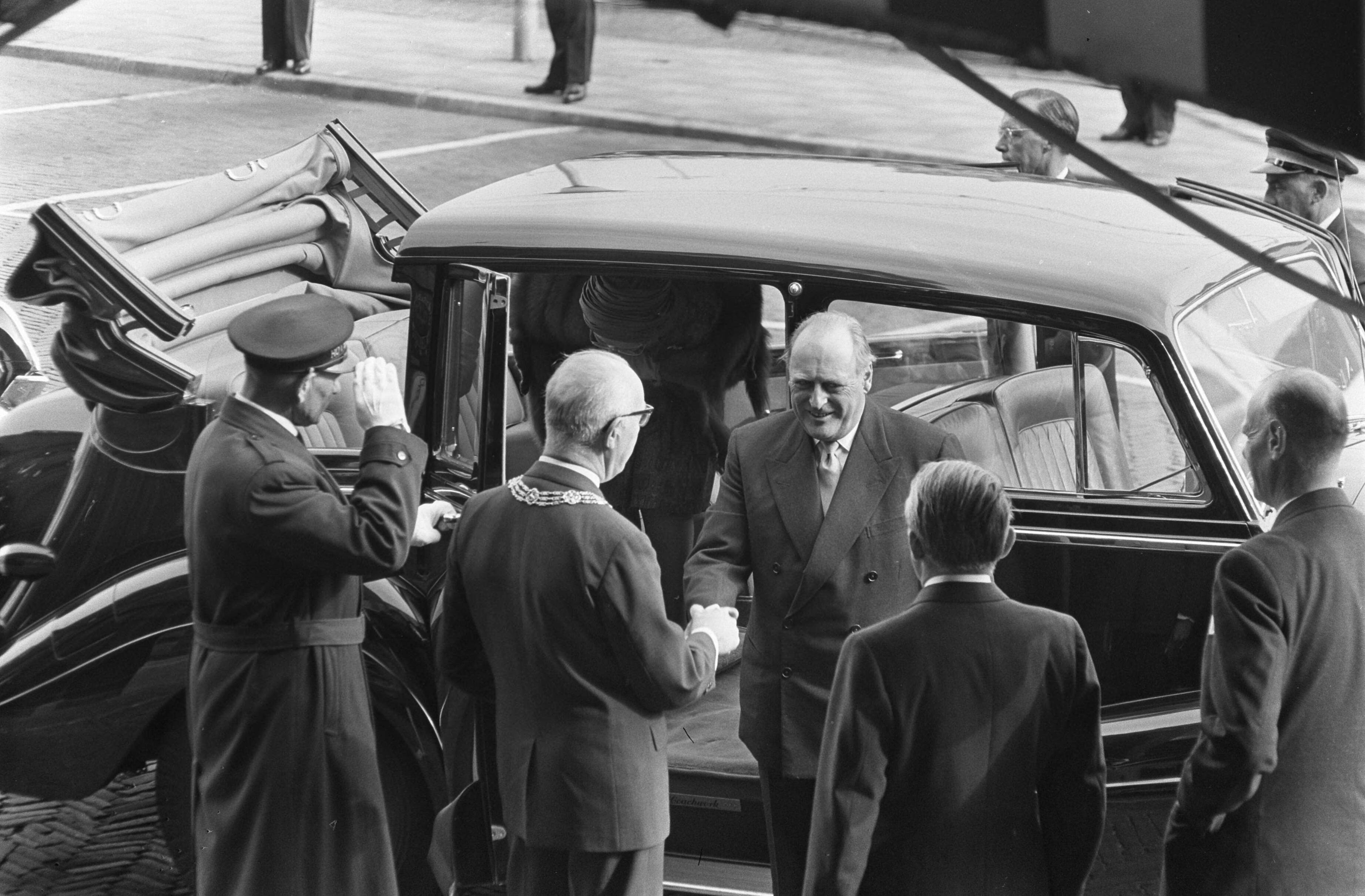 Staatsbezoek van koning Olav van Noorwegen aan Nederland — Bezoek koning Olav van Noorwegen aan Den Haag. Aankomst van koning Olav bij het Scheveningse Kürhaus, Hij wordt verwelkomd door burgemeester Kolfschoten en mr. J. Klaasesz, Commissaris der Koningin in Zuid-Holland — Foto: Nijs, Jac. de / Anefo. Licentie: Set B: Rechtenvrij / Publiek Domein. Bron: Nationaal Archief. http://hdl.handle.net/10648/aa787668-d0b4-102d-bcf8-003048976d84