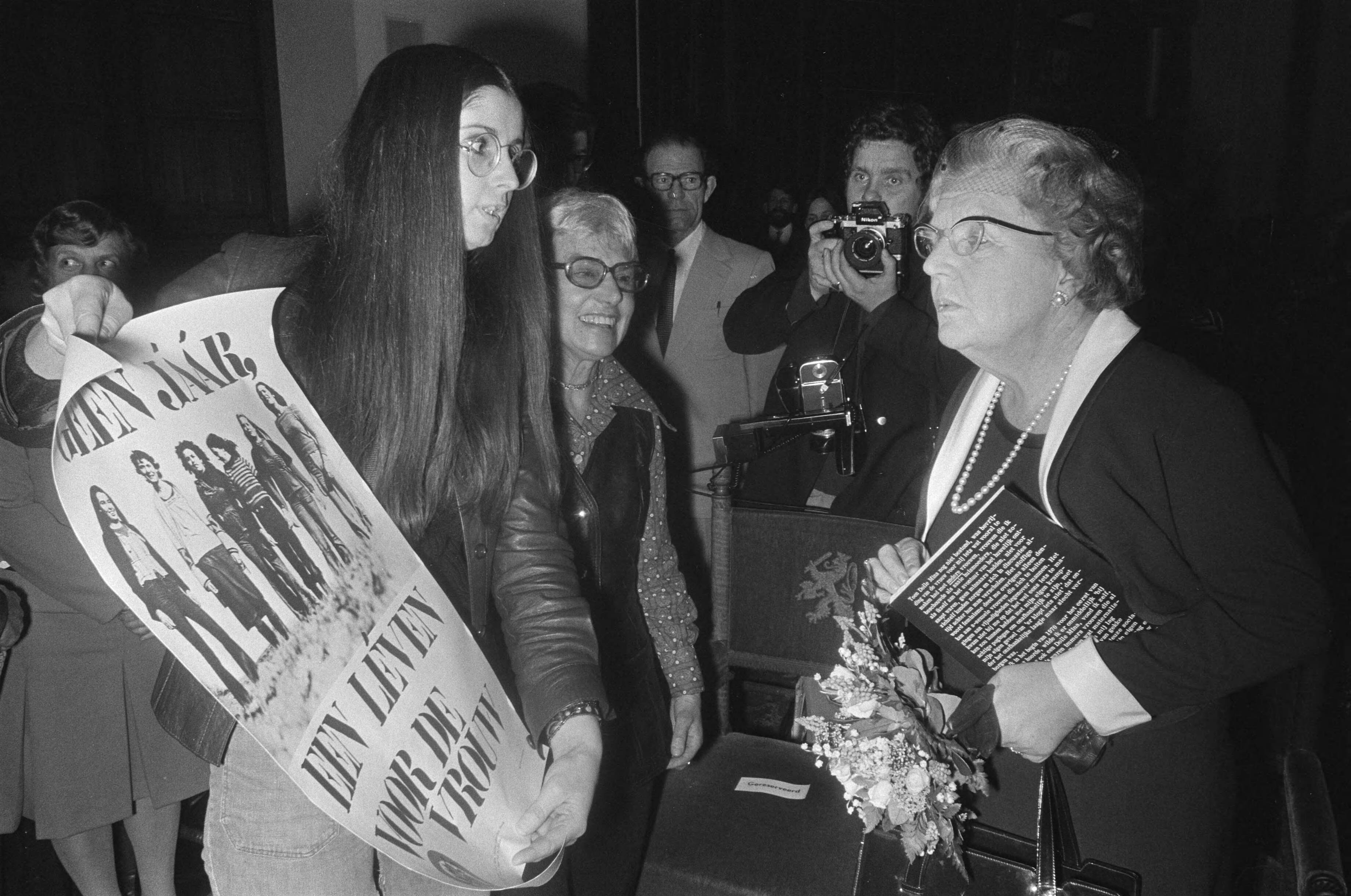 Fotocollectie Anefo — HM bij bijeenkomst Nationaal Comite "Internationale Jaar van de Vrouw 1975" in Ridderzaal in Den Haag ; HM bekijkt protestaffiche van Dolle Mina — Foto: Peters, Hans / Anefo. Licentie: Set B: Rechtenvrij / Publiek Domein. Bron: Nationaal Archief. http://hdl.handle.net/10648/ac6193b0-d0b4-102d-bcf8-003048976d84