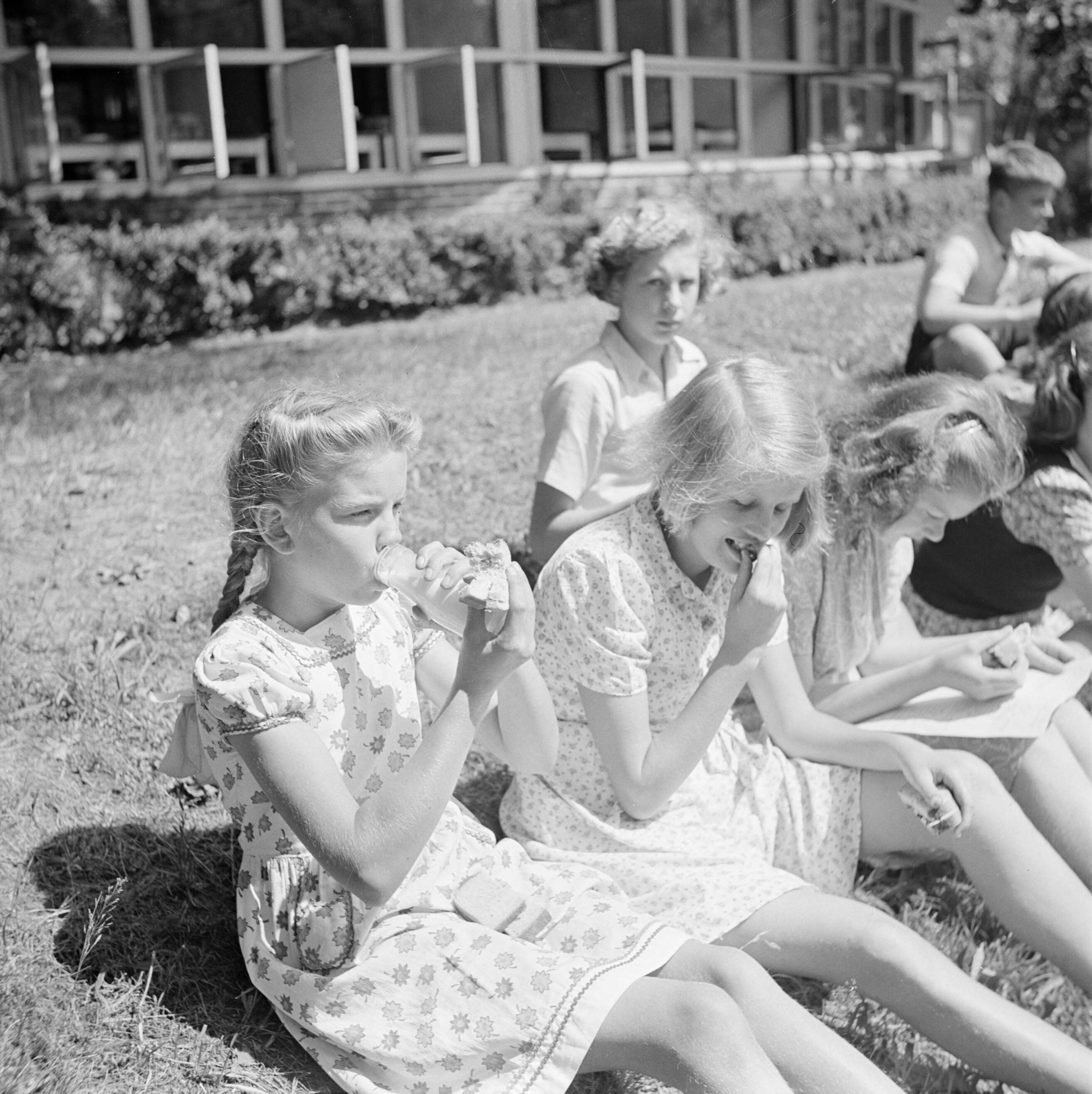 De prinsessen Beatrix en Irene op de Werkplaats Kindergemeenschap van Kees Boeke te Bilthoven — Leerlingen pauzeren in de tuin — Foto: Poll, Willem van de. Licentie: Set B: Rechtenvrij / Publiek Domein. Bron: Nationaal Archief. http://hdl.handle.net/10648/aee8047a-d0b4-102d-bcf8-003048976d84