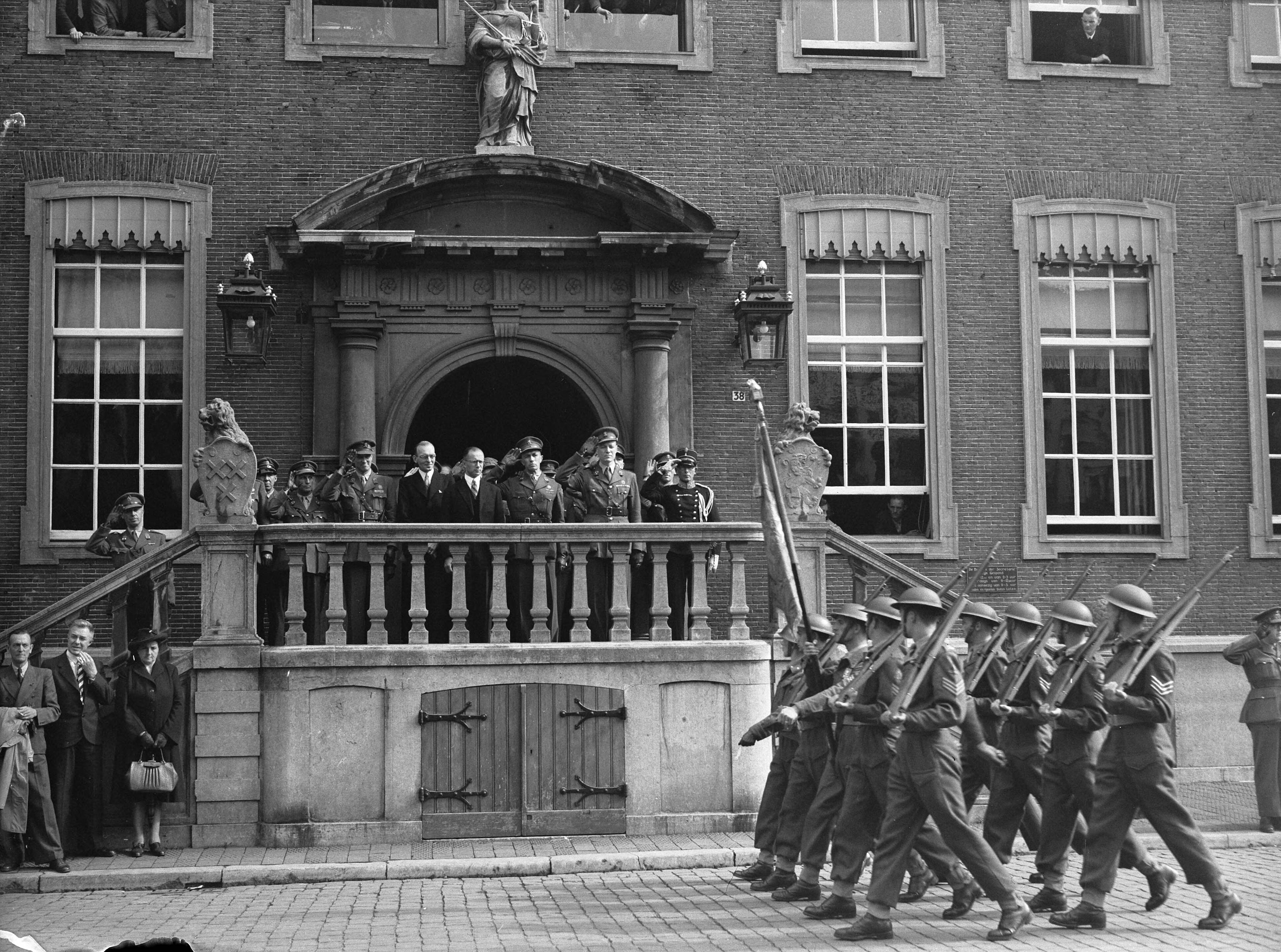 Fotocollectie Anefo — Afscheidsparade opleidingscursus Reserve-officieren Breda. Militair defilé in Breda. Vaandelwacht passeert het stadhuis — Foto: Wisman, Bram / Anefo. Licentie: Set B: Rechtenvrij / Publiek Domein. Bron: Nationaal Archief. http://hdl.handle.net/10648/a8ad0218-d0b4-102d-bcf8-003048976d84