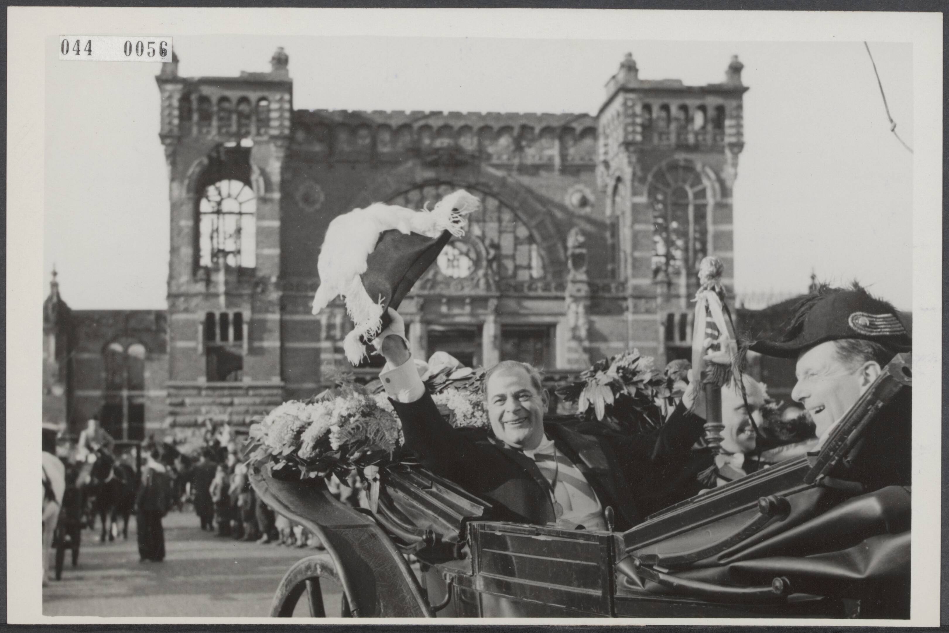Fotocollectie Elsevier Binnenland — Aankomst van prins Carnaval in Den Bosch. De intocht van de prins vanaf het in de oorlog gebombardeerde station. Prins Amadeiro XVI groet vanuit zijn rijtuig de Bossenaren — Foto: Fotograaf Onbekend / Anefo. Licentie: Set B: Rechtenvrij / Publiek Domein. Bron: Nationaal Archief. http://hdl.handle.net/10648/adfabe22-d0b4-102d-bcf8-003048976d84