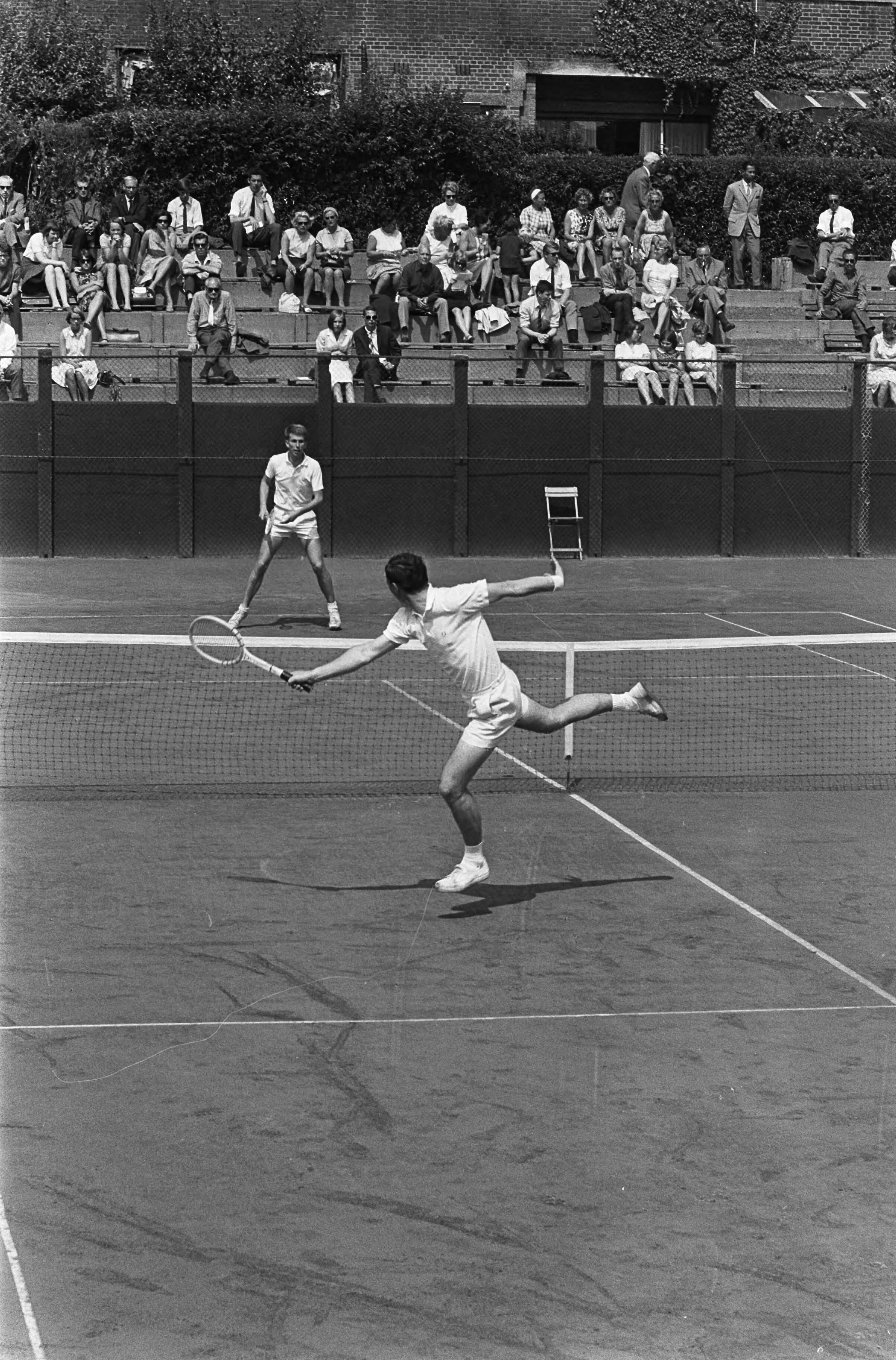 Fotocollectie Anefo — Nederlandse tenniskampioenschappen op de METS-banen te Scheveningen. Evert Schneider (op achtergrond) tegen Piet Veentjer in de 3e ronde. Schneider won met 6-4, 6-2 en 6-2 — Foto: Koch, Eric / Anefo. Licentie: Set B: Rechtenvrij / Publiek Domein. Bron: Nationaal Archief. http://hdl.handle.net/10648/aaba6726-d0b4-102d-bcf8-003048976d84