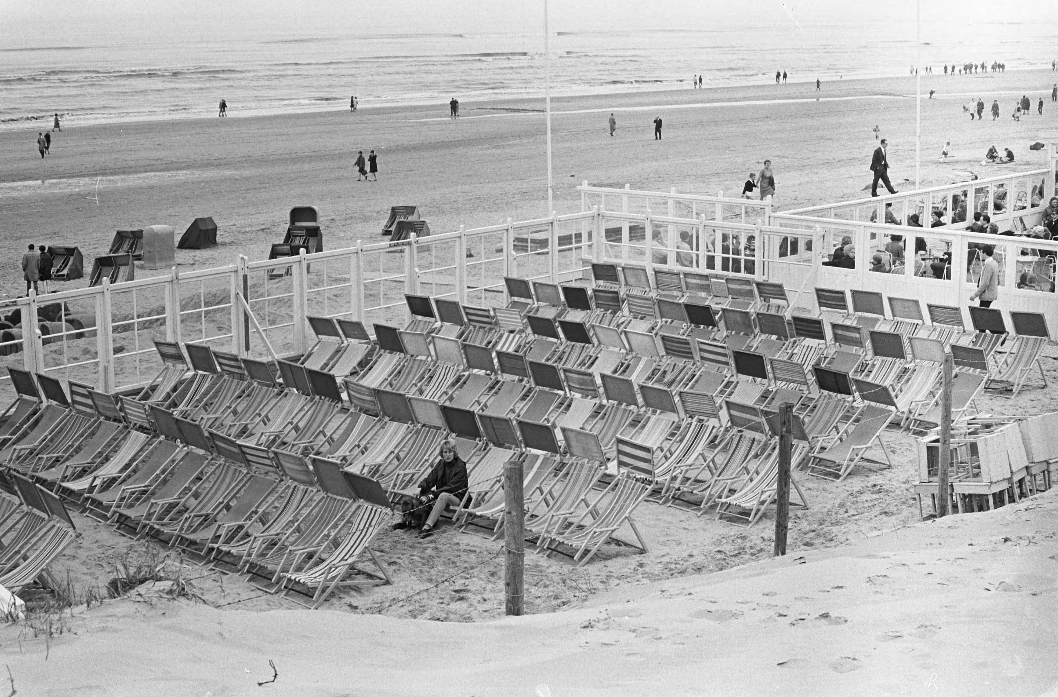 Fotocollectie Anefo — Eenzame badgasten temidden van lege ligstoelen op terras Zandvoort — Foto: Kroon, Ron / Anefo. Licentie: Set B: Rechtenvrij / Publiek Domein. Bron: Nationaal Archief. http://hdl.handle.net/10648/aae472c8-d0b4-102d-bcf8-003048976d84
