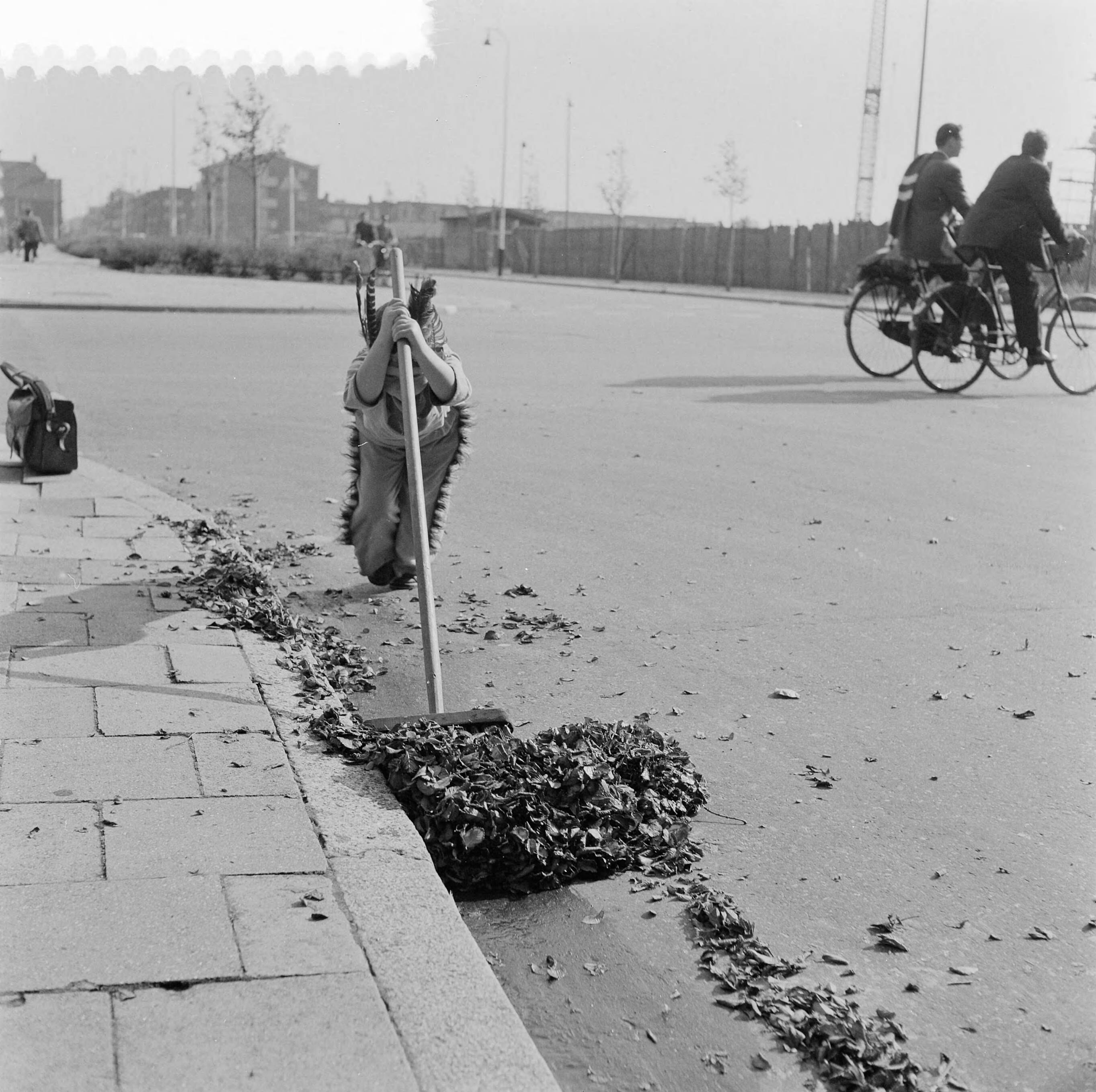 Fotocollectie Anefo — Jongetje, verkleed als Indiaan, dat bladeren wegveegt aan de Sportlaan te Den Haag — Foto: Behrens, Herbert F. / Anefo. Licentie: Set B: Rechtenvrij / Publiek Domein. Bron: Nationaal Archief. http://hdl.handle.net/10648/a96aeee0-d0b4-102d-bcf8-003048976d84