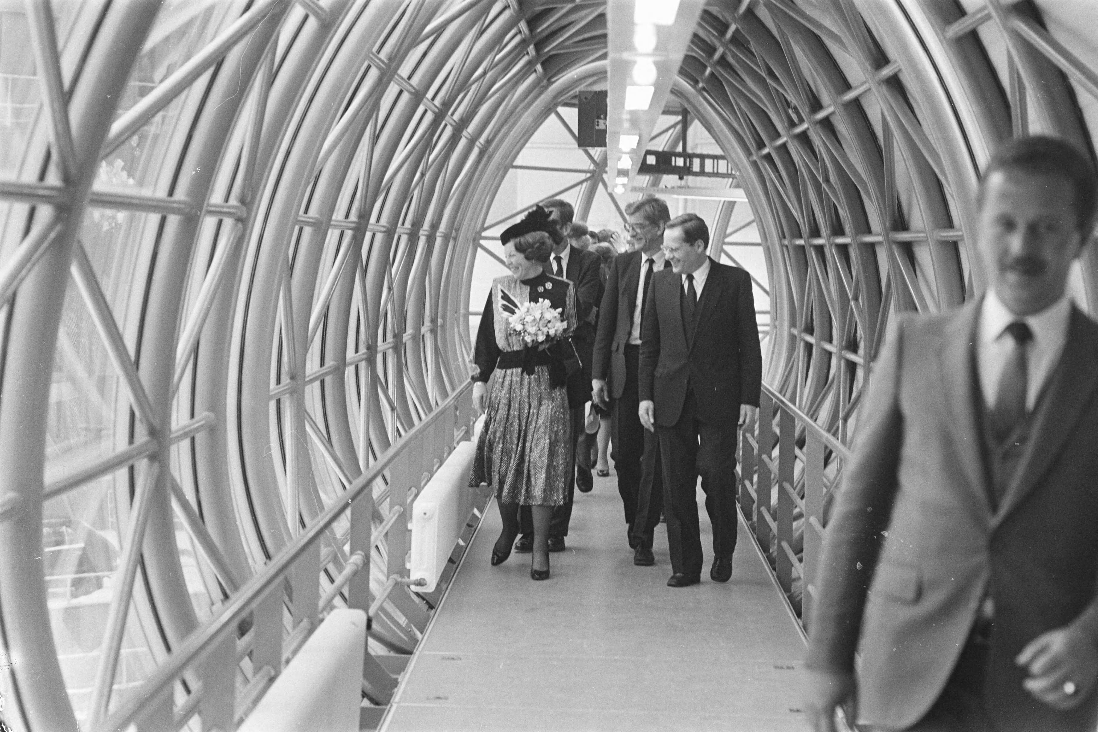 Fotocollectie Anefo — Beatrix opent het nieuwe Ministerie van O&W in Zoetermeer; Beatrix en Deetman lopen door een slurf van het ene gebouw naar het ander — Foto: Croes, Rob C. / Anefo. Licentie: Set B: Rechtenvrij / Publiek Domein. Bron: Nationaal Archief. http://hdl.handle.net/10648/ad41c048-d0b4-102d-bcf8-003048976d84