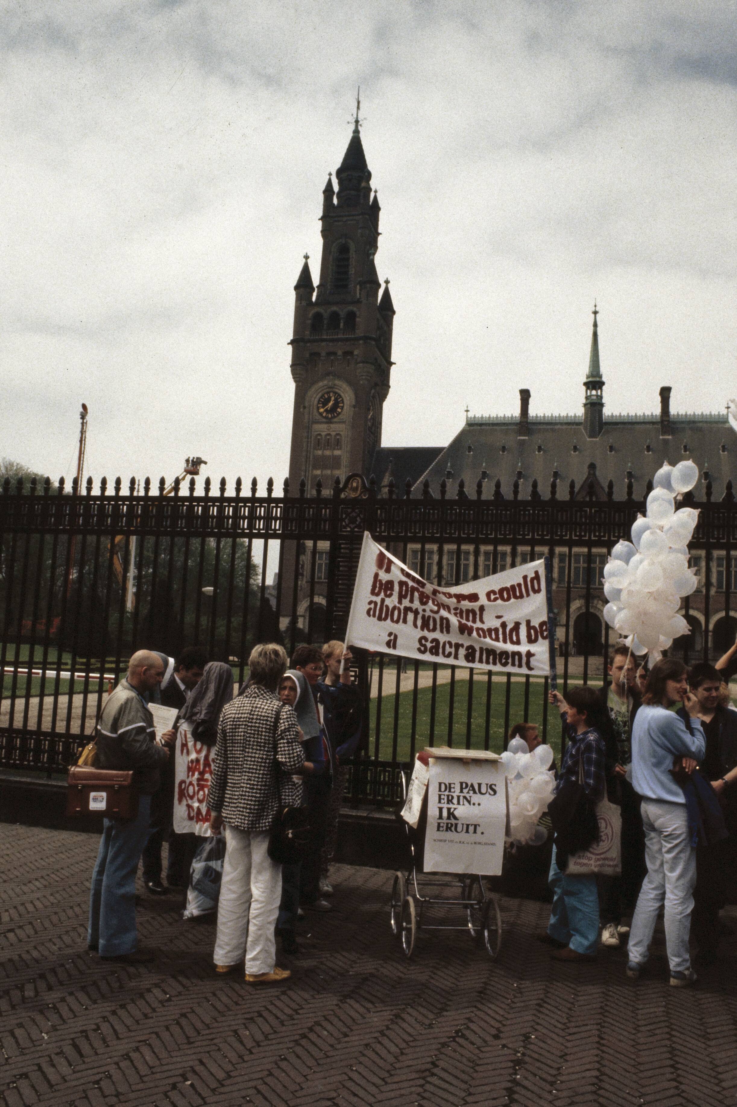 Fotocollectie Anefo — Pausbezoek aan Nederland; demonstranten tegen de Paus bij het Vredespaleis in Den Haag — Foto: Bogaerts, Rob / Anefo. Licentie: Set B: Rechtenvrij / Publiek Domein. Bron: Nationaal Archief. http://hdl.handle.net/10648/ad8ba97e-d0b4-102d-bcf8-003048976d84