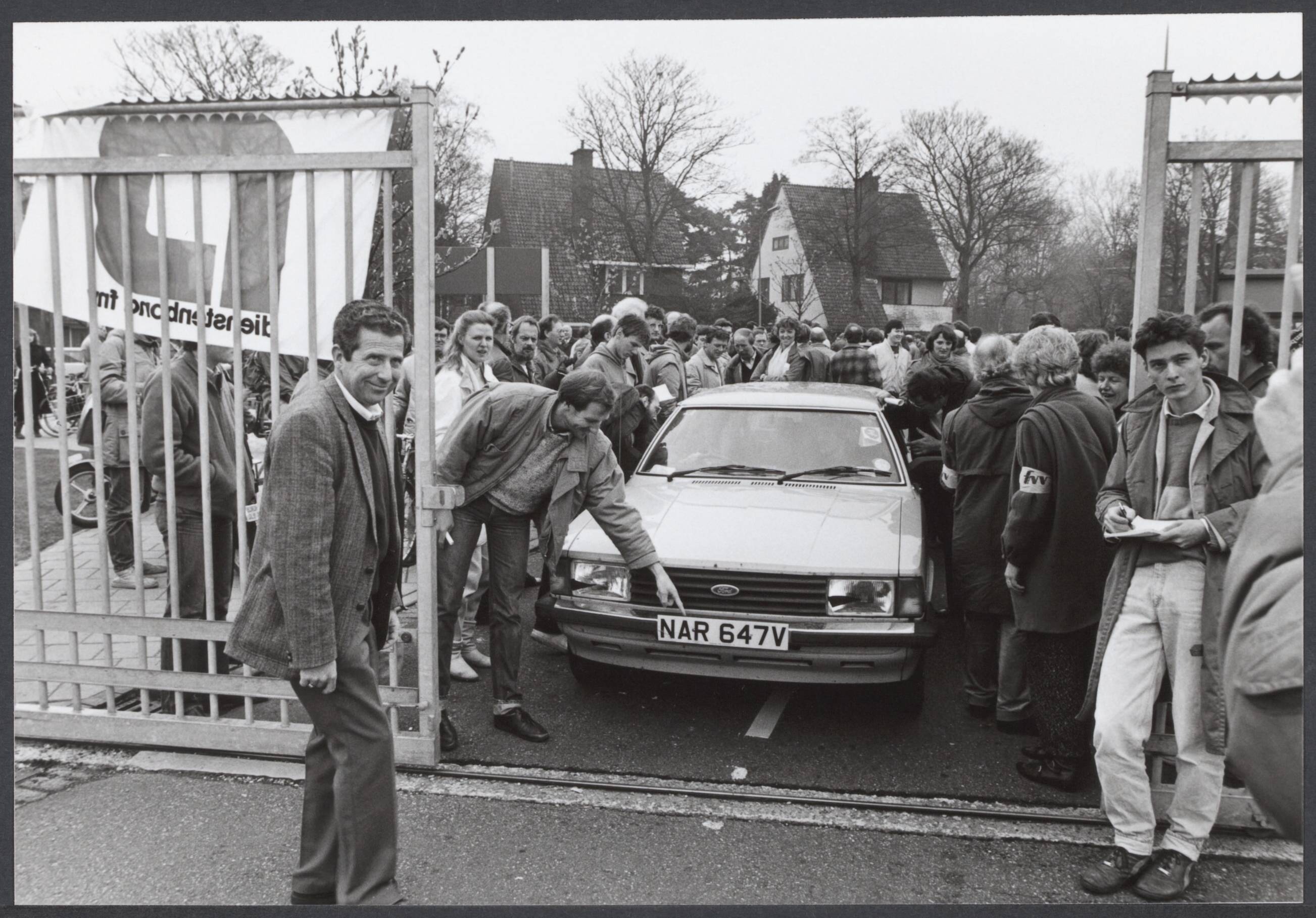 Radioraad, radio- en televisiepolitiek — Vanmorgen is bij de omroepen een staking begonnen die tot vanavond 12.00 zal duren. Dit uit protest tegen het besluit van minister Brinkman om de omroep-cao alsnog af te wijzen. Slechts een enkele auto wed toegelaten op het NOS-terrein. Het betrof hier een ploeg Engelse technici — Foto: Croes, Rob C. / Anefo. Licentie: Set B: Rechtenvrij / Publiek Domein. Bron: Nationaal Archief. http://hdl.handle.net/10648/a20bafba-841f-b609-f9af-9cac0f39f5f6