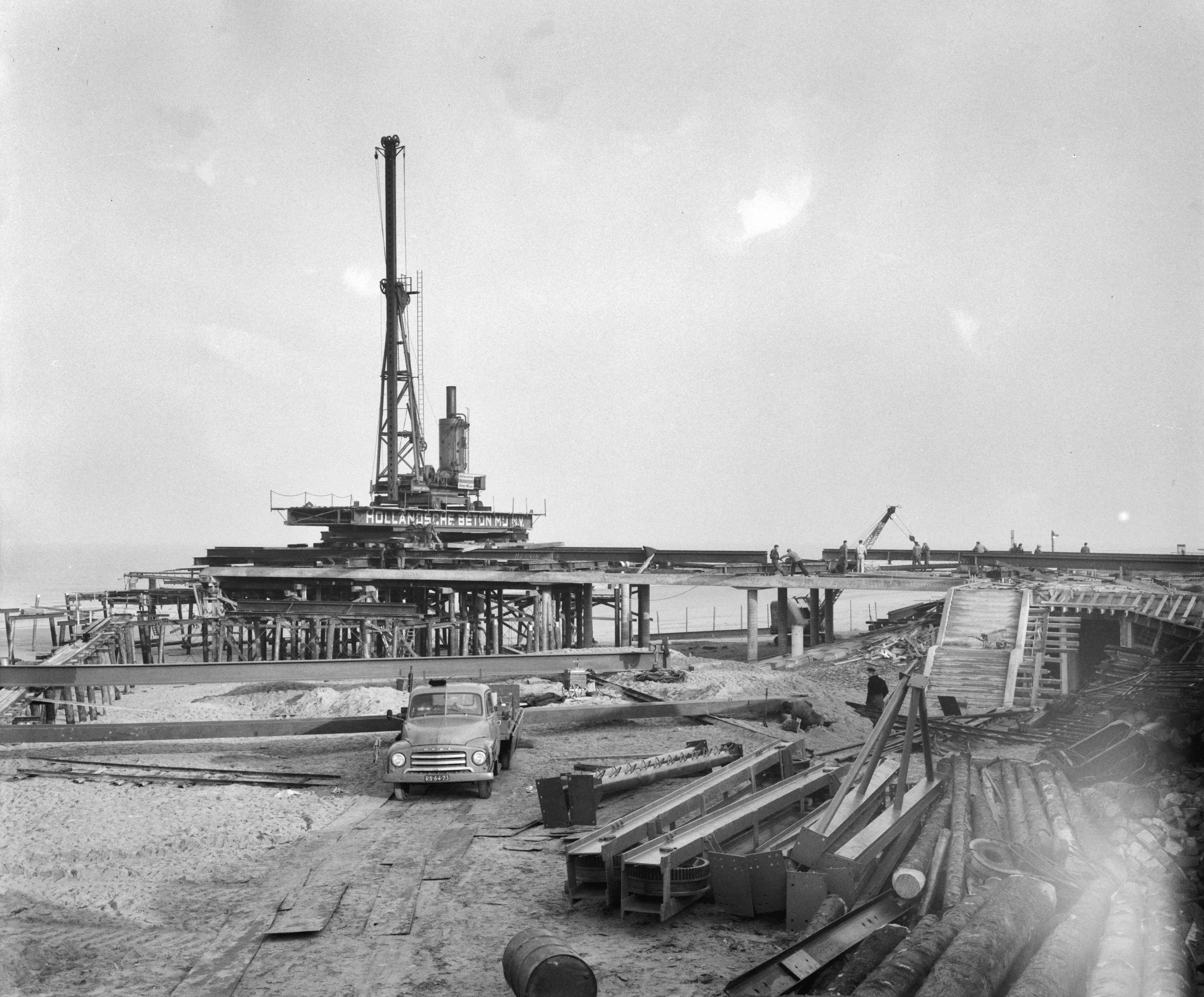 Fotocollectie Anefo — Werkzaamheden aan de nieuwe Pier te Scheveningen — Foto: Behrens, Herbert F. / Anefo. Licentie: Set B: Rechtenvrij / Publiek Domein. Bron: Nationaal Archief. http://hdl.handle.net/10648/a9a72f5e-d0b4-102d-bcf8-003048976d84