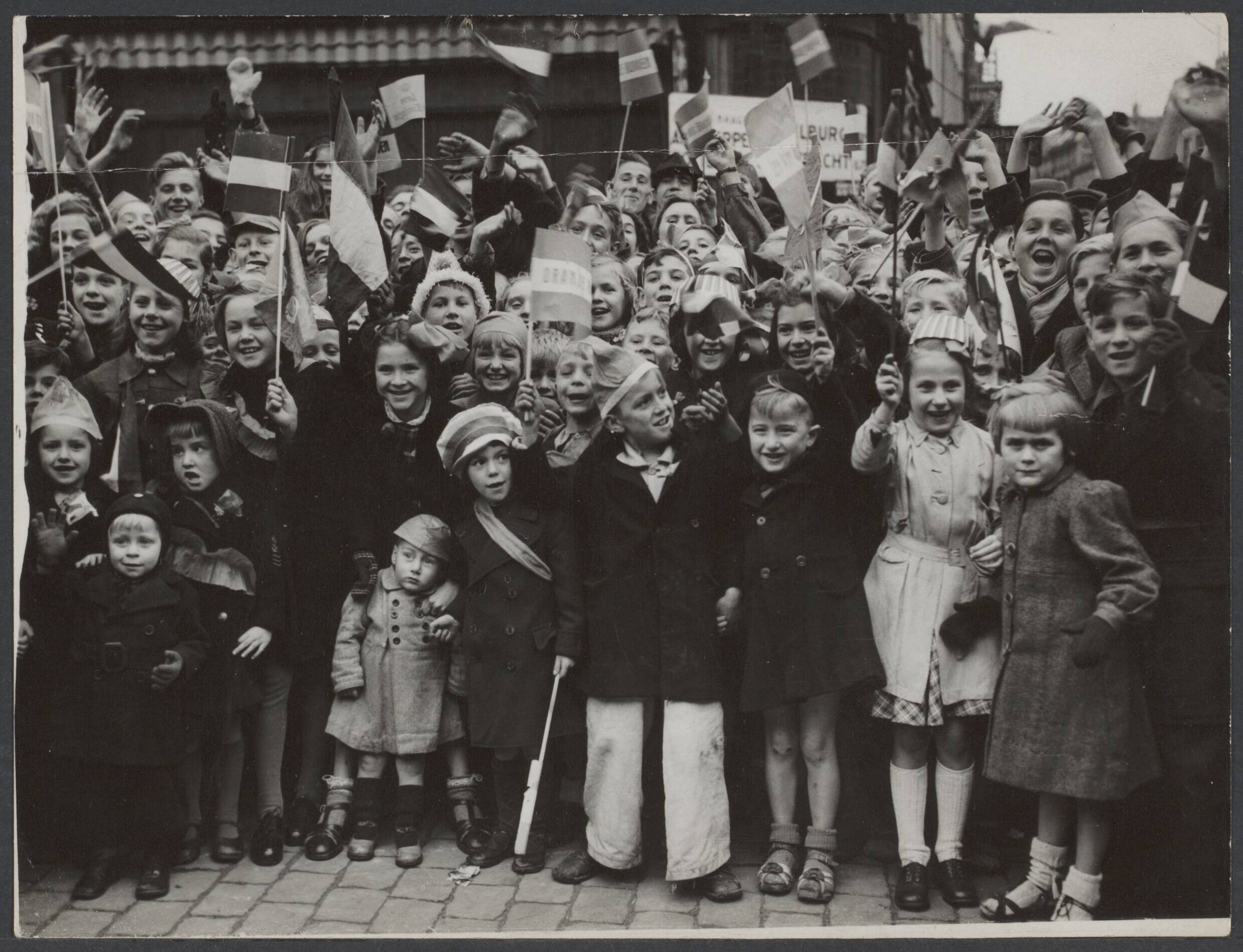 Bevrijding Nederland 1944 [bevat ook foto's uit 1945] — Poolse troepen bevrijden Breda. Grote aantallen Bredase kinderen begroeten de geallieerde bevrijders met vlaggen en glimlachen — Foto: New York Times / Rechtenvrij. Licentie: Set B: Rechtenvrij / Publiek Domein. Bron: Nationaal Archief. http://hdl.handle.net/10648/c707c094-0306-7140-d992-1b8ffed2a416