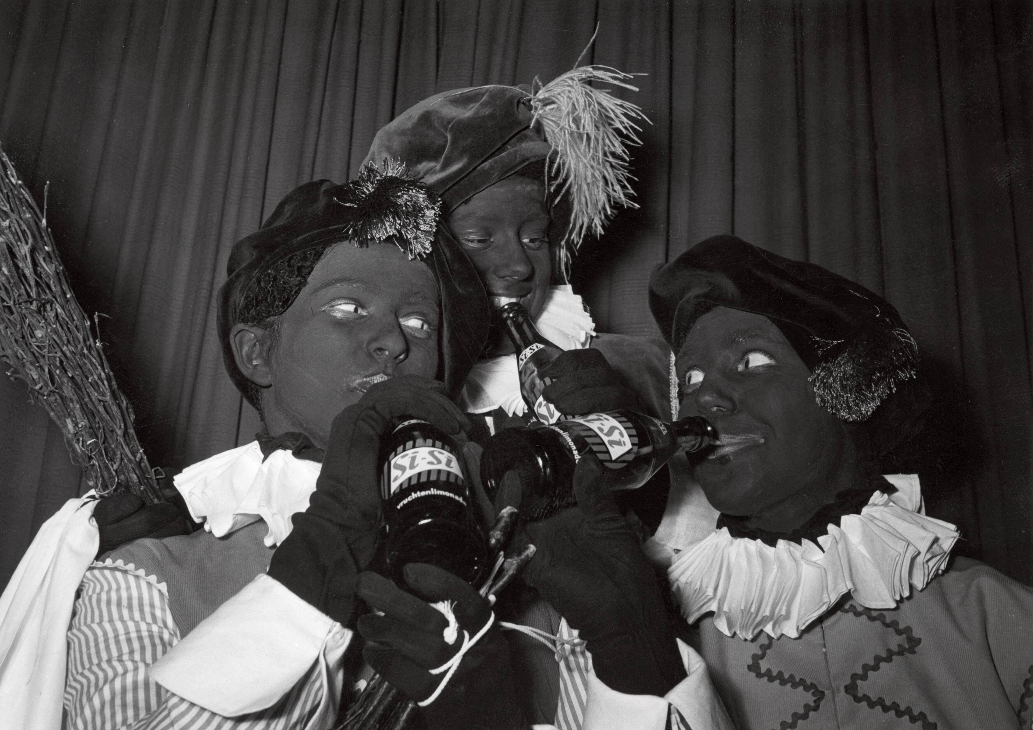 Collectie nader te bepalen — [Sinterklaasfeest N.V. Drukkerij De Spaarnestad in Haarlem] [Drie Zwarte Pieten drinken uit een flesje Sisi-limonade] — Foto: Fotograaf Onbekend / Fotobureau onbekend / Spaarnestad Photo (05887). Licentie: Set B: Rechtenvrij / Publiek Domein. Bron: Nationaal Archief. http://hdl.handle.net/10648/35429da6-404a-a382-e063-6df0900a6686