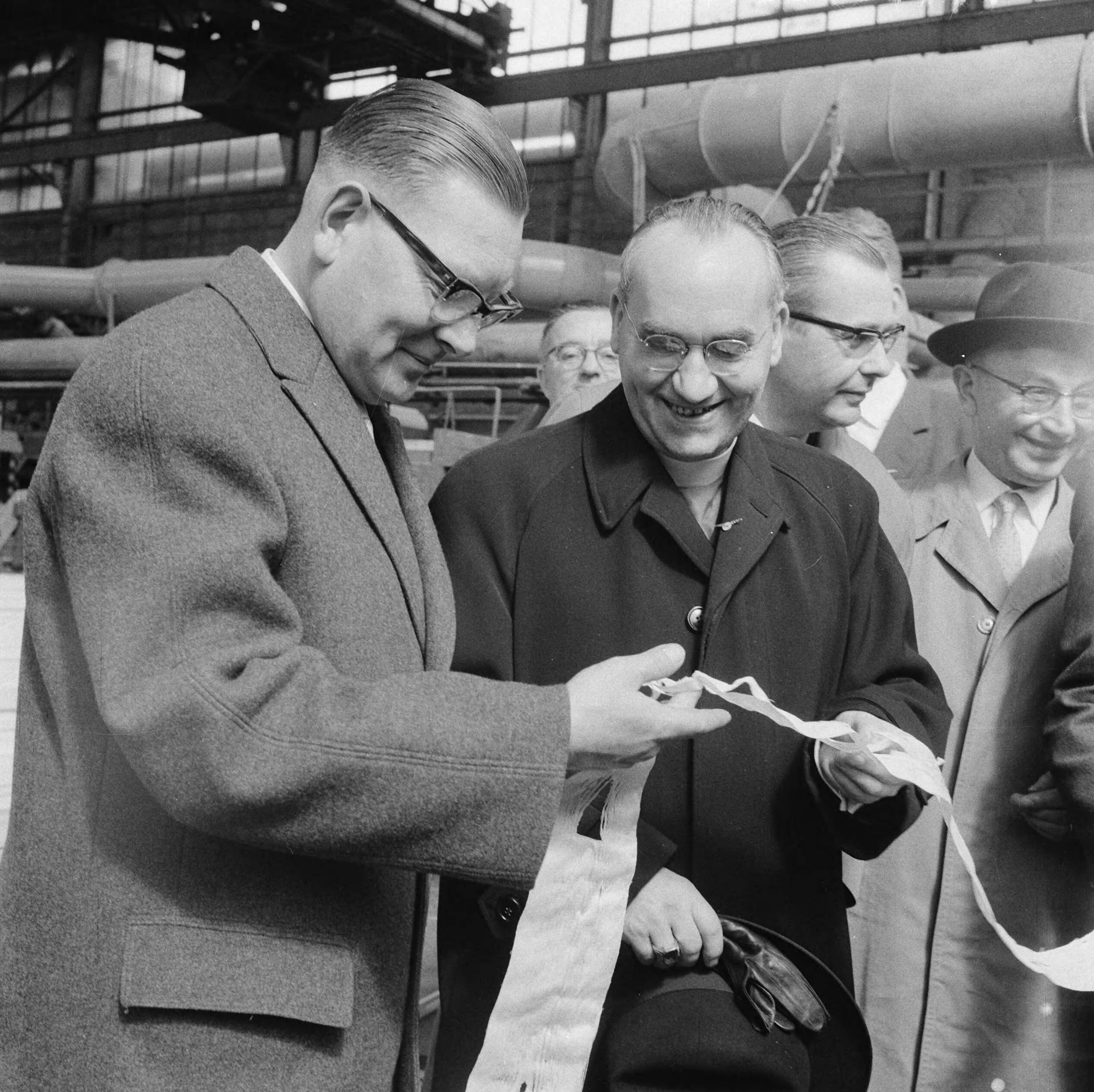 Fotocollectie Anefo — Werkbezoek van mgr. dr. J.A.E. van Dodewaard, bisschop van Haarlem, aan de Zaanstreek. De bisschop en de burgemeester van Zaandam, Gé Franken (links) in een fabriek — Foto: Nijs, Jac. de / Anefo. Licentie: Set B: Rechtenvrij / Publiek Domein. Bron: Nationaal Archief. http://hdl.handle.net/10648/a9d485da-d0b4-102d-bcf8-003048976d84
