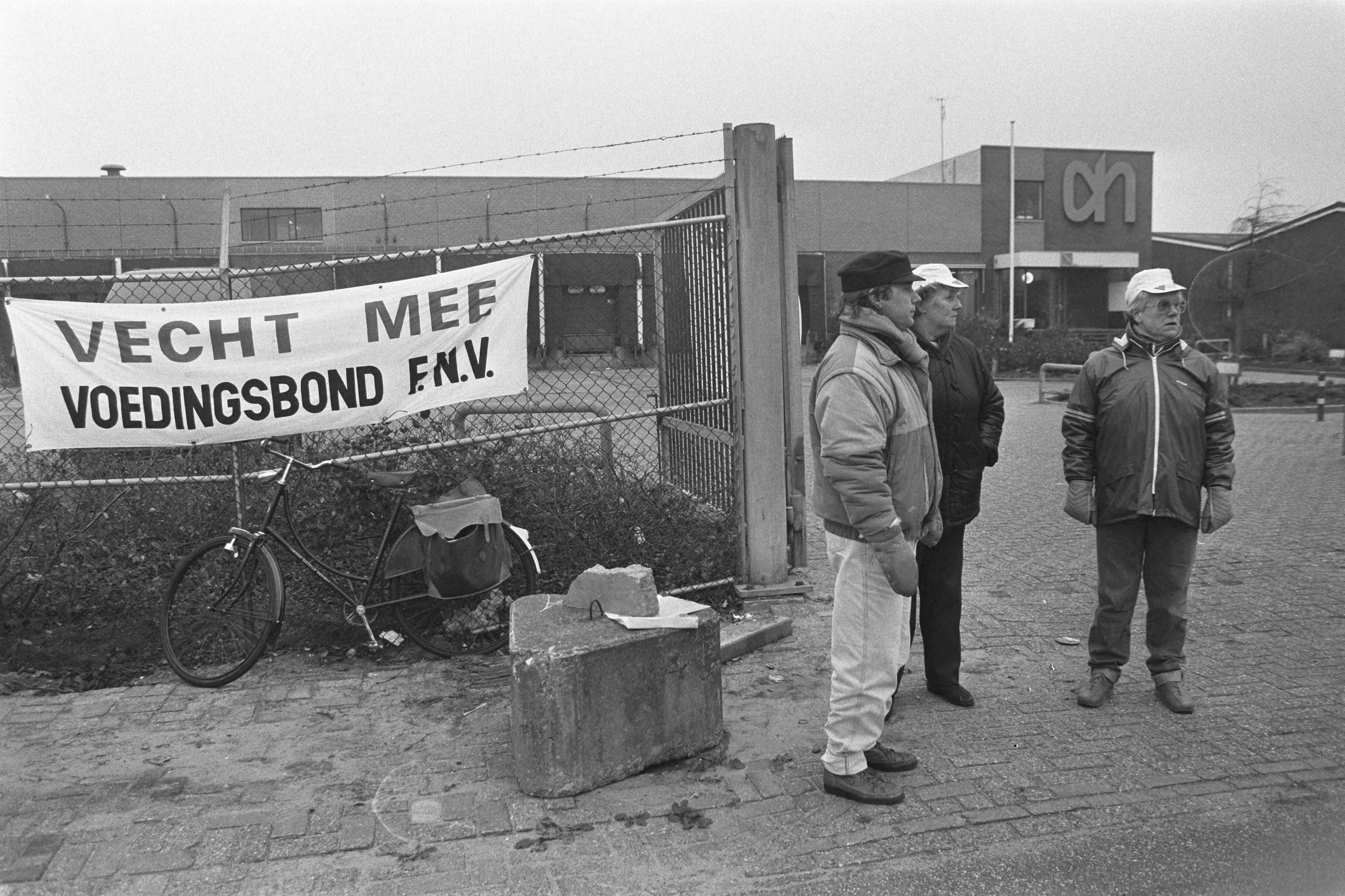 Fotocollectie Anefo — Staking Centr. Slagerij AHOLD Zaandam; postende stakers voor de poort — Foto: Molendijk, Bart / Anefo. Licentie: Set B: Rechtenvrij / Publiek Domein. Bron: Nationaal Archief. http://hdl.handle.net/10648/ad5a2eee-d0b4-102d-bcf8-003048976d84