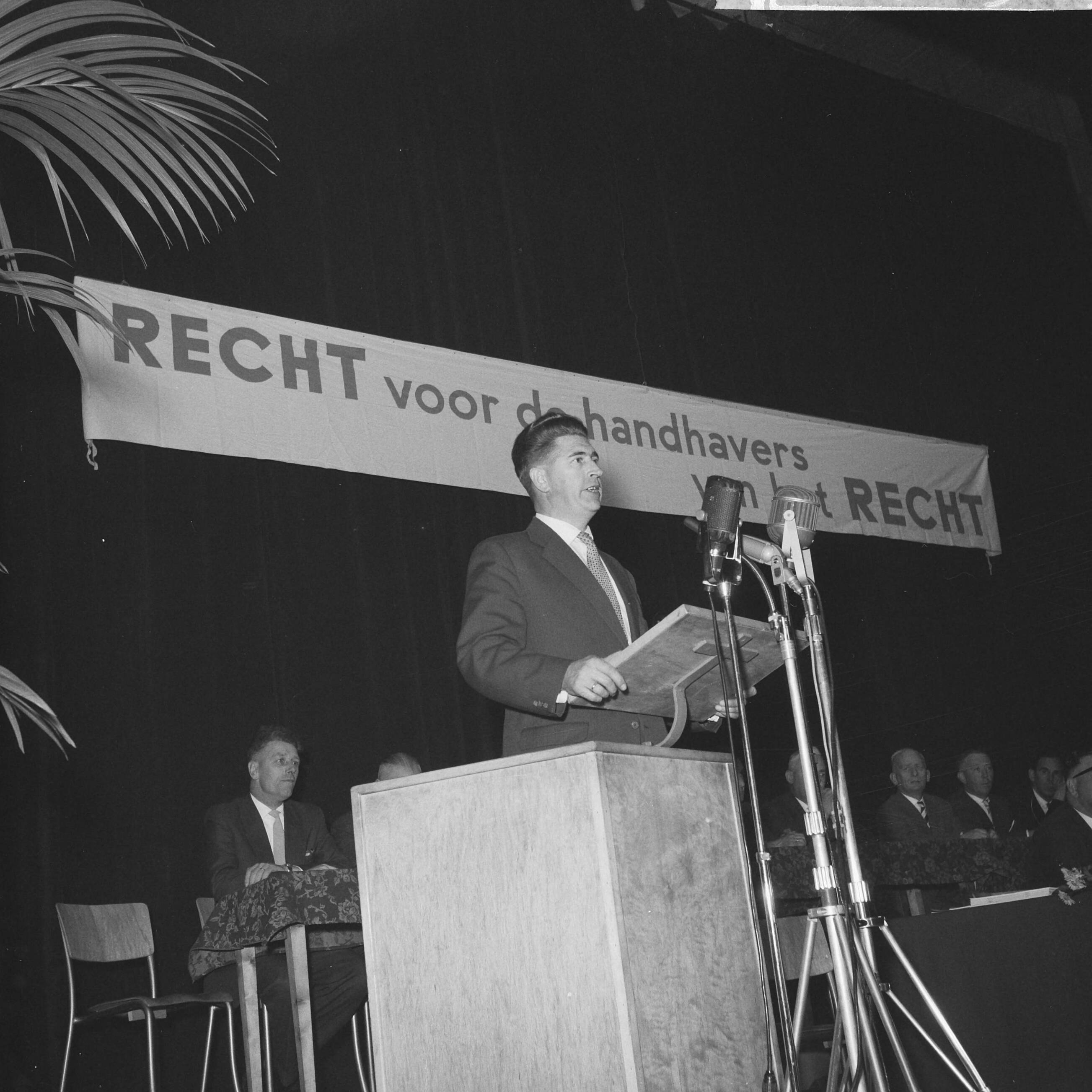 Fotocollectie Anefo — Protestvergadering door politie-ambtenaren tegen loonpolitiek van de regering in het gebouw voor Kunsten en Wetenschappen te Den Haag — Foto: Pot, Harry / Anefo. Licentie: Set B: Rechtenvrij / Publiek Domein. Bron: Nationaal Archief. http://hdl.handle.net/10648/a9bc3d04-d0b4-102d-bcf8-003048976d84