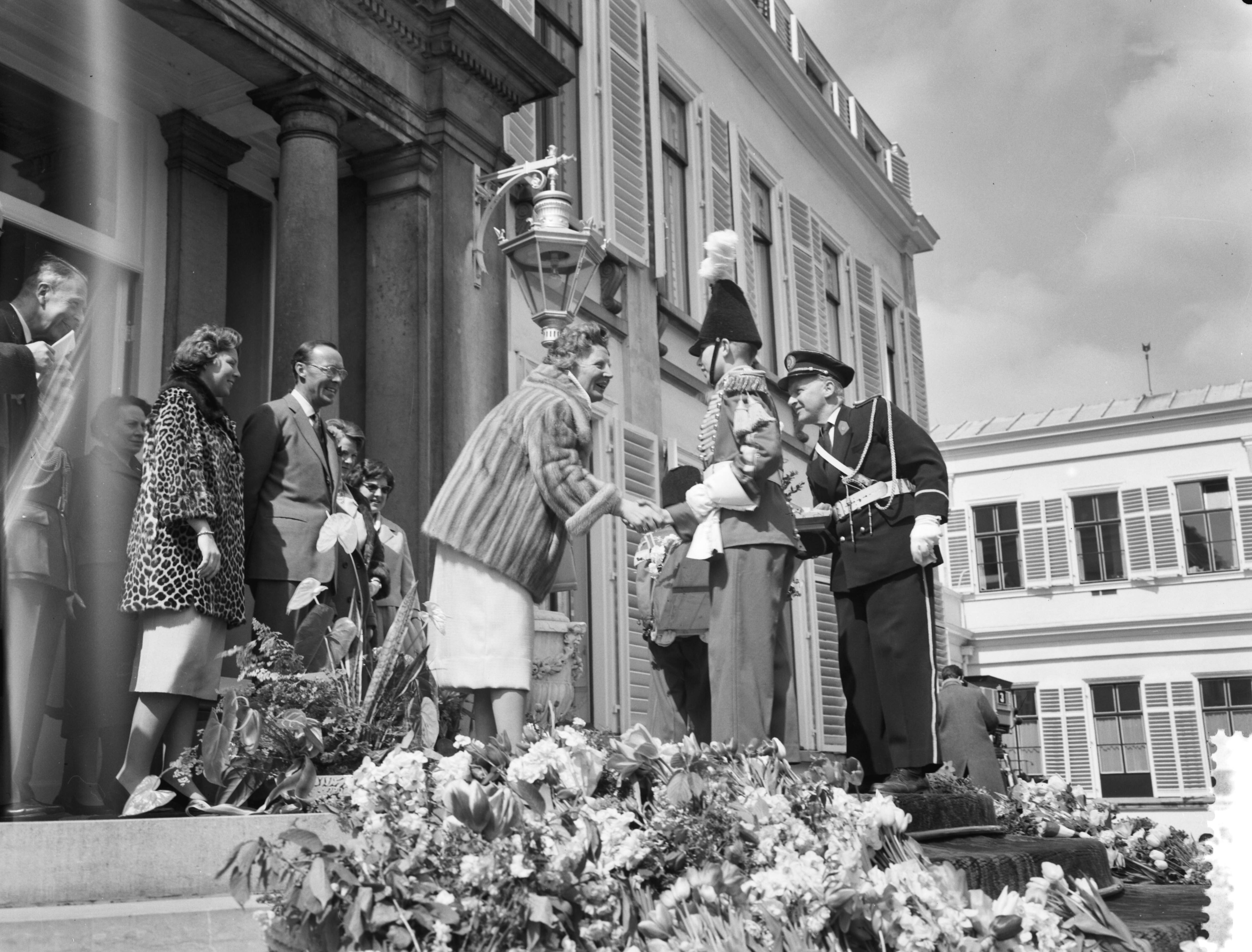 Koninginnedag 1960 — Het muziekkorps biedt koningin Juliana een cadeau aan — Foto: Rossem, Wim van / Anefo. Licentie: Set B: Rechtenvrij / Publiek Domein. Bron: Nationaal Archief. http://hdl.handle.net/10648/a9ad81ba-d0b4-102d-bcf8-003048976d84