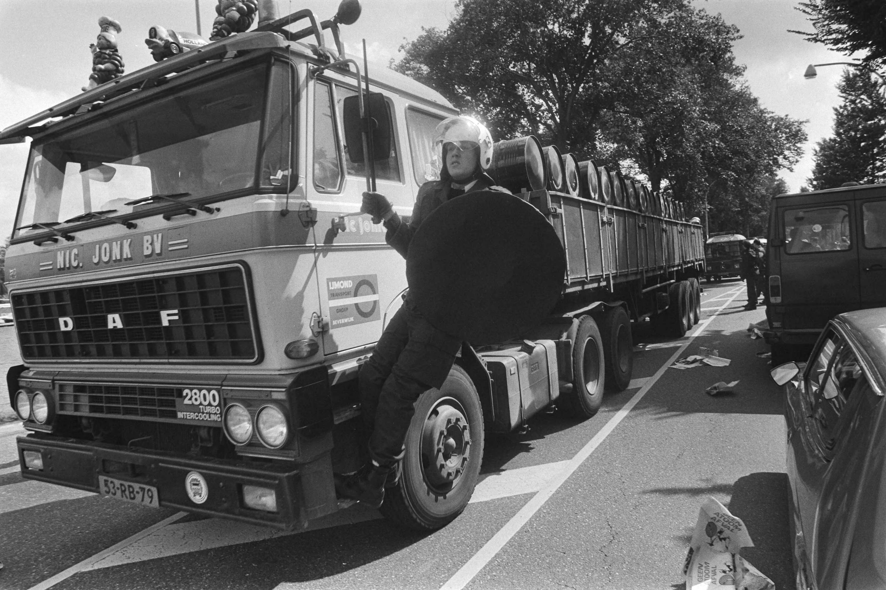Fotocollectie Anefo — Akties tegen transport radioactief afval van Petten naar Den Helder ; autos met afval met ME-er voorop en achterop — Foto: Dijk, Hans van / Anefo. Licentie: Set B: Rechtenvrij / Publiek Domein. Bron: Nationaal Archief. http://hdl.handle.net/10648/ad1ceea8-d0b4-102d-bcf8-003048976d84