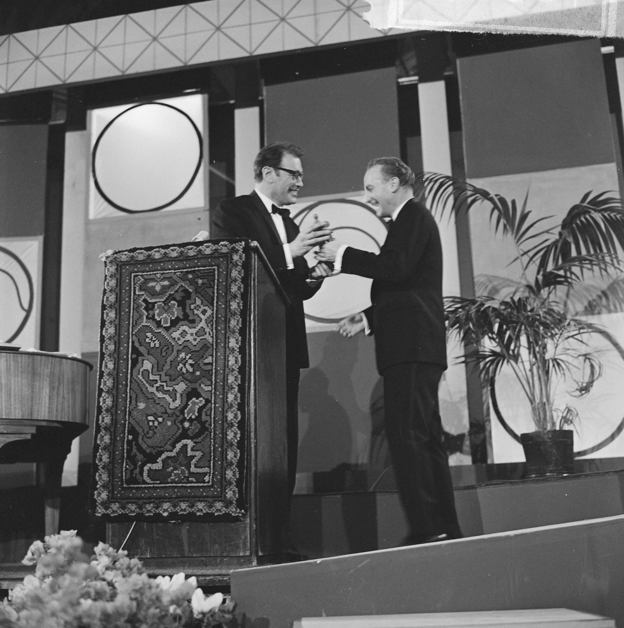 Grand Gala du Disque 1963 — Grand Gala du Disque Populair in het Kurhaus te Scheveningen. Wim Sonneveld ontvangt de Edison van presentator Godfried Bomans — Foto: Koch, Eric / Anefo. Licentie: Set B: Rechtenvrij / Publiek Domein. Bron: Nationaal Archief. http://hdl.handle.net/10648/aa498506-d0b4-102d-bcf8-003048976d84