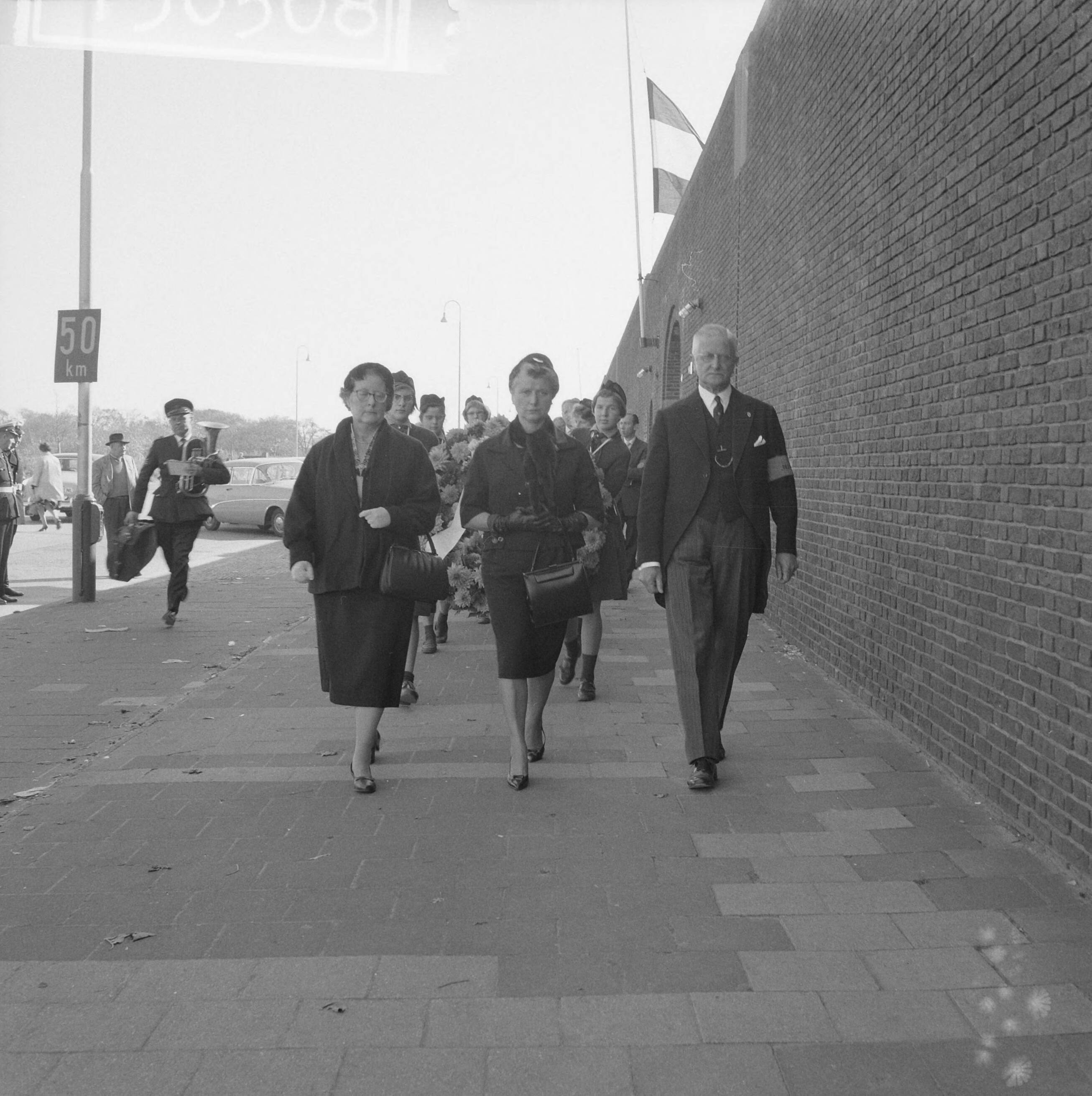 Fotocollectie Anefo — Herdenking"Oranjehotel" te Scheveningen. De particulier secretaresse van prinses Wilhelmina, mej. J.C.M.M. Geldens op weg naar Dodencel 601 waar zij namens de prinses een krans zal leggen. Naast haar de voorzitter van Stichting Oranjehotel, prof. mr. R.P. Cleveringa — Foto: Lindeboom, Henk / Anefo. Licentie: Set B: Rechtenvrij / Publiek Domein. Bron: Nationaal Archief. http://hdl.handle.net/10648/a9e77820-d0b4-102d-bcf8-003048976d84