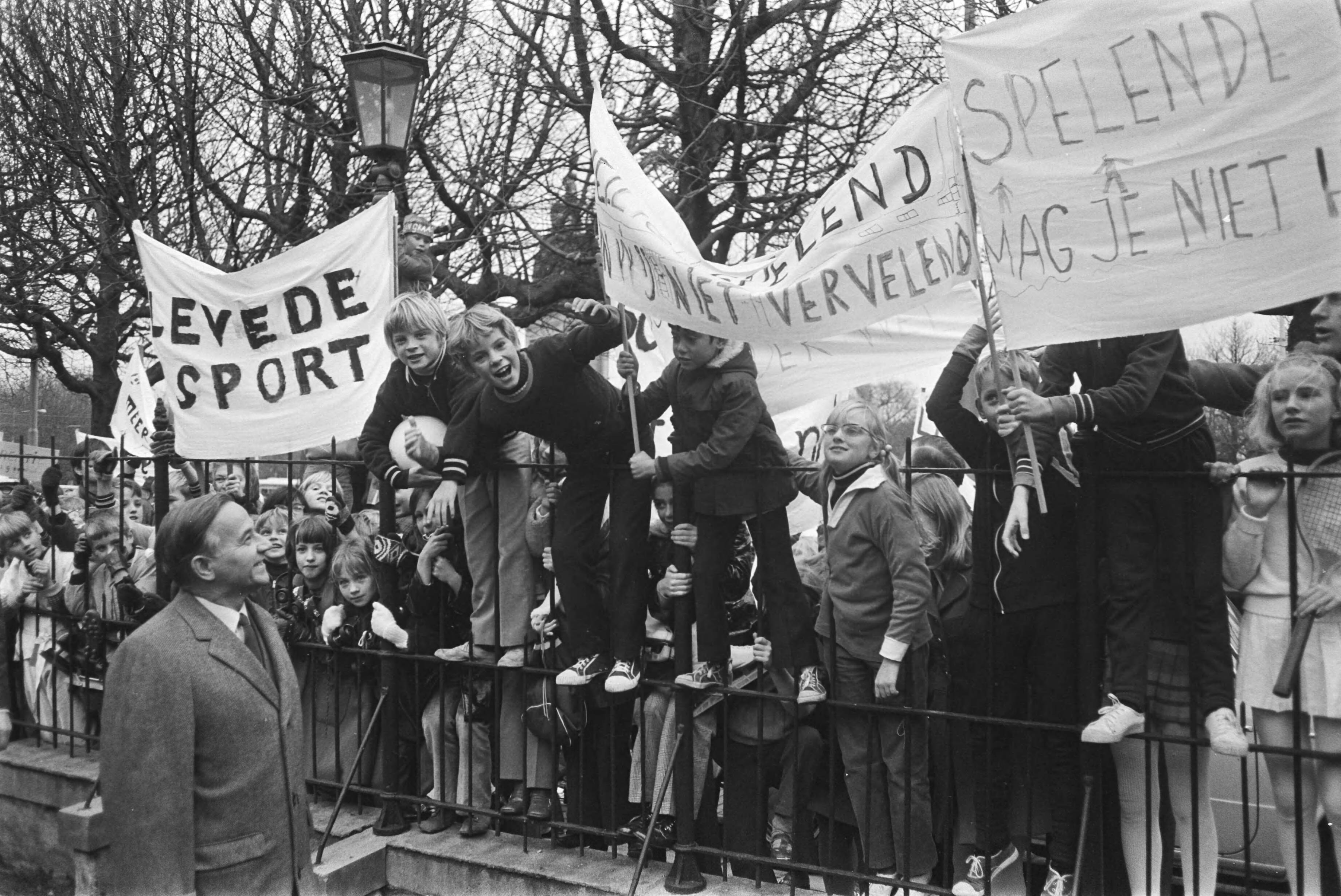 Fotocollectie Anefo — 500 lagere schoolkinderen vragen Premier De Jong om speel- en leefruimte, Den Haag ; Premier De Jong leest buiten de spandoeken kinderen — Foto: Koch, Eric / Anefo. Licentie: Set B: Rechtenvrij / Publiek Domein. Bron: Nationaal Archief. http://hdl.handle.net/10648/abaa16f4-d0b4-102d-bcf8-003048976d84