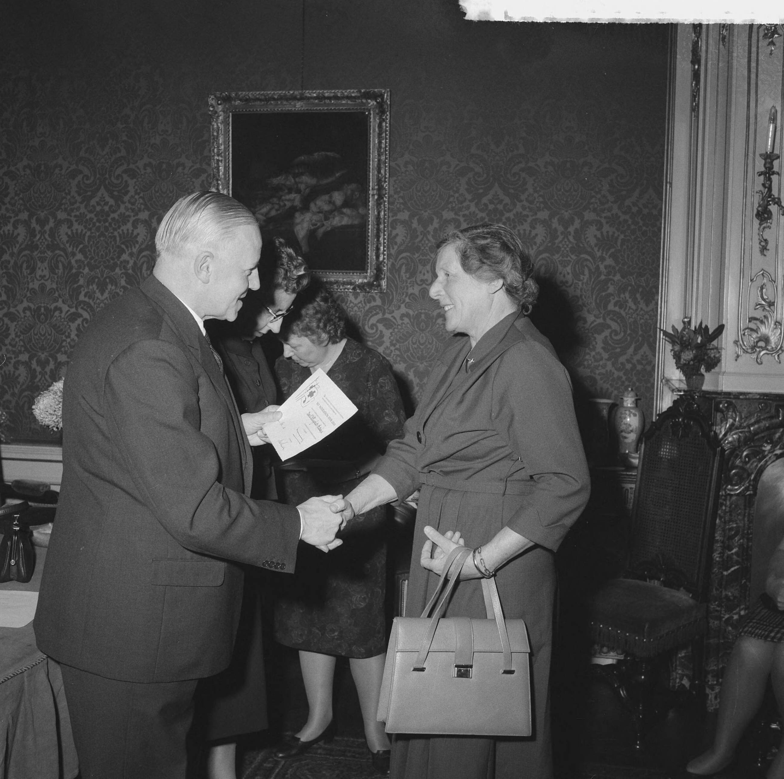 Fotocollectie Anefo — Uitreiking Rode Kruis campagnespeldjes te Den Haag. Notaris R. Remmelts, vice-voorzitter van de Haagse afdeling, reikt oorkonde uit — Foto: Behrens, Herbert F. / Anefo. Licentie: Set B: Rechtenvrij / Publiek Domein. Bron: Nationaal Archief. http://hdl.handle.net/10648/a9c22534-d0b4-102d-bcf8-003048976d84