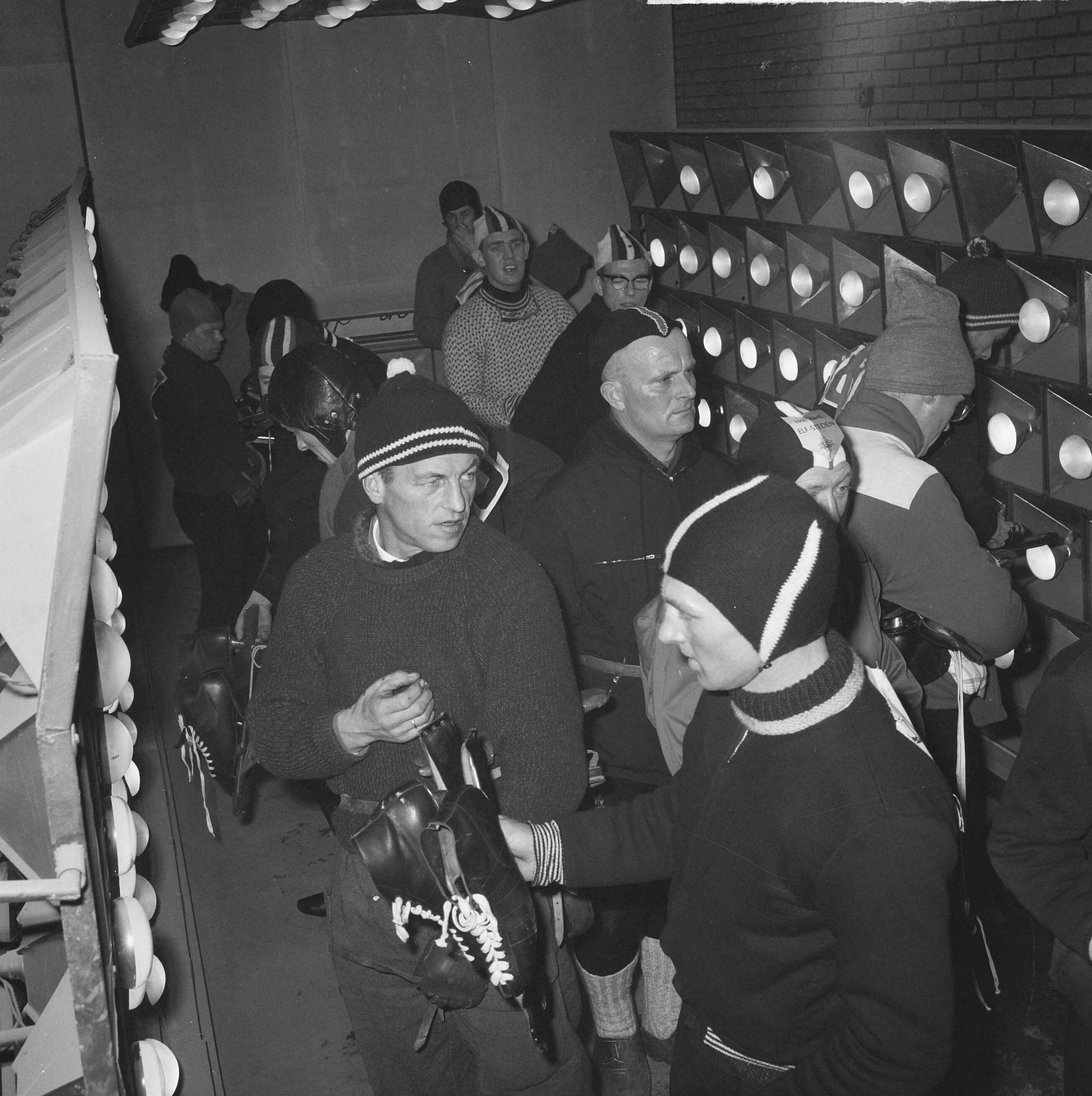 Elfstedentocht 1963 — Elfstedentocht 1963. Deelnemers warmen zich voor de start in garage Postuma te Leeuwarden — Foto: Nijs, Jac. de / Anefo. Licentie: Set B: Rechtenvrij / Publiek Domein. Bron: Nationaal Archief. http://hdl.handle.net/10648/aa268d58-d0b4-102d-bcf8-003048976d84