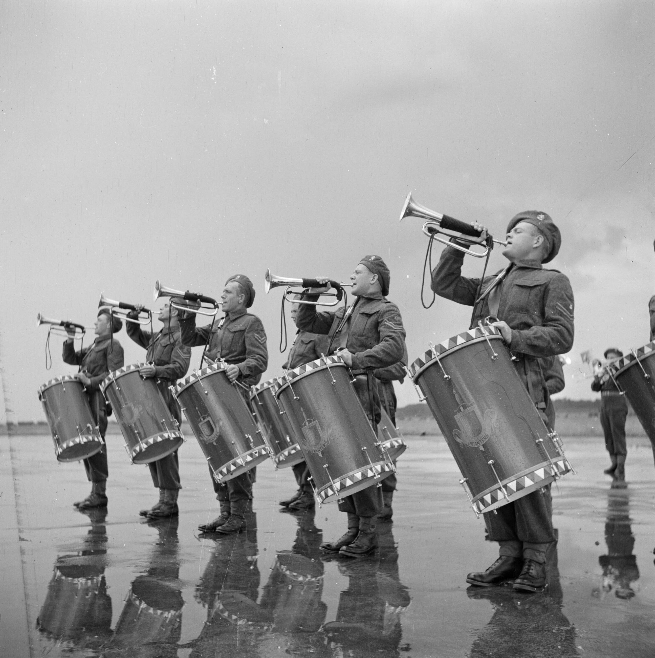 Uitreiking van de Militaire Willems-Orde en andere onderscheidingen door koningin Wilhelmina in aanwezigheid van de overige leden van de koninklijke familie op de vliegbasis Soesterberg — Tamboerkorps — Foto: Poll, Willem van de. Licentie: Set B: Rechtenvrij / Publiek Domein. Bron: Nationaal Archief. http://hdl.handle.net/10648/aee8fcfe-d0b4-102d-bcf8-003048976d84