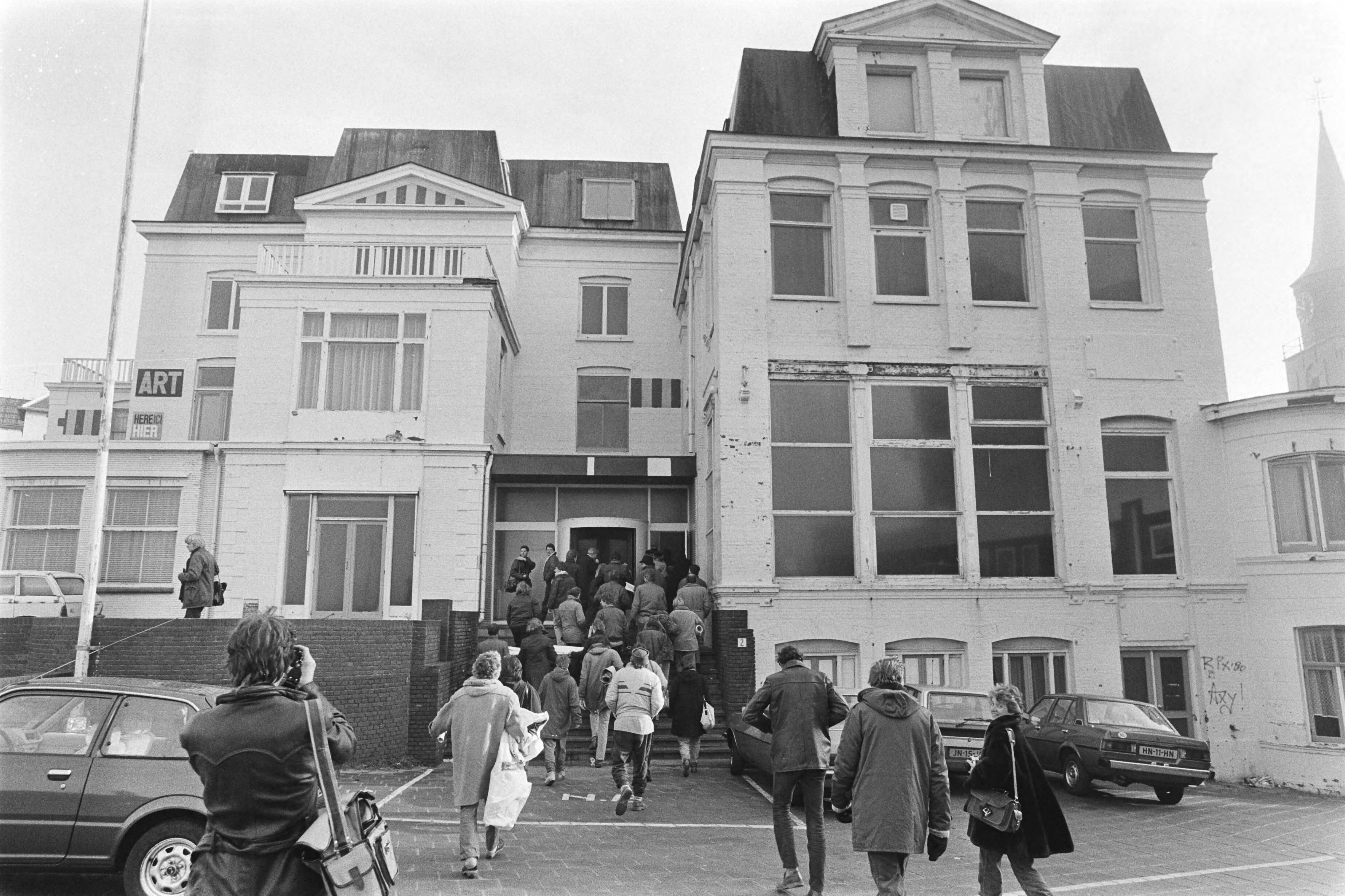 Fotocollectie Anefo — Kunstenaars bezetten een pand van premier Lubbers in Scheveningen; de kunstenaars gaan het pand binnen — Foto: Antonisse, Marcel / Anefo. Licentie: Set B: Rechtenvrij / Publiek Domein. Bron: Nationaal Archief. http://hdl.handle.net/10648/ad3281aa-d0b4-102d-bcf8-003048976d84