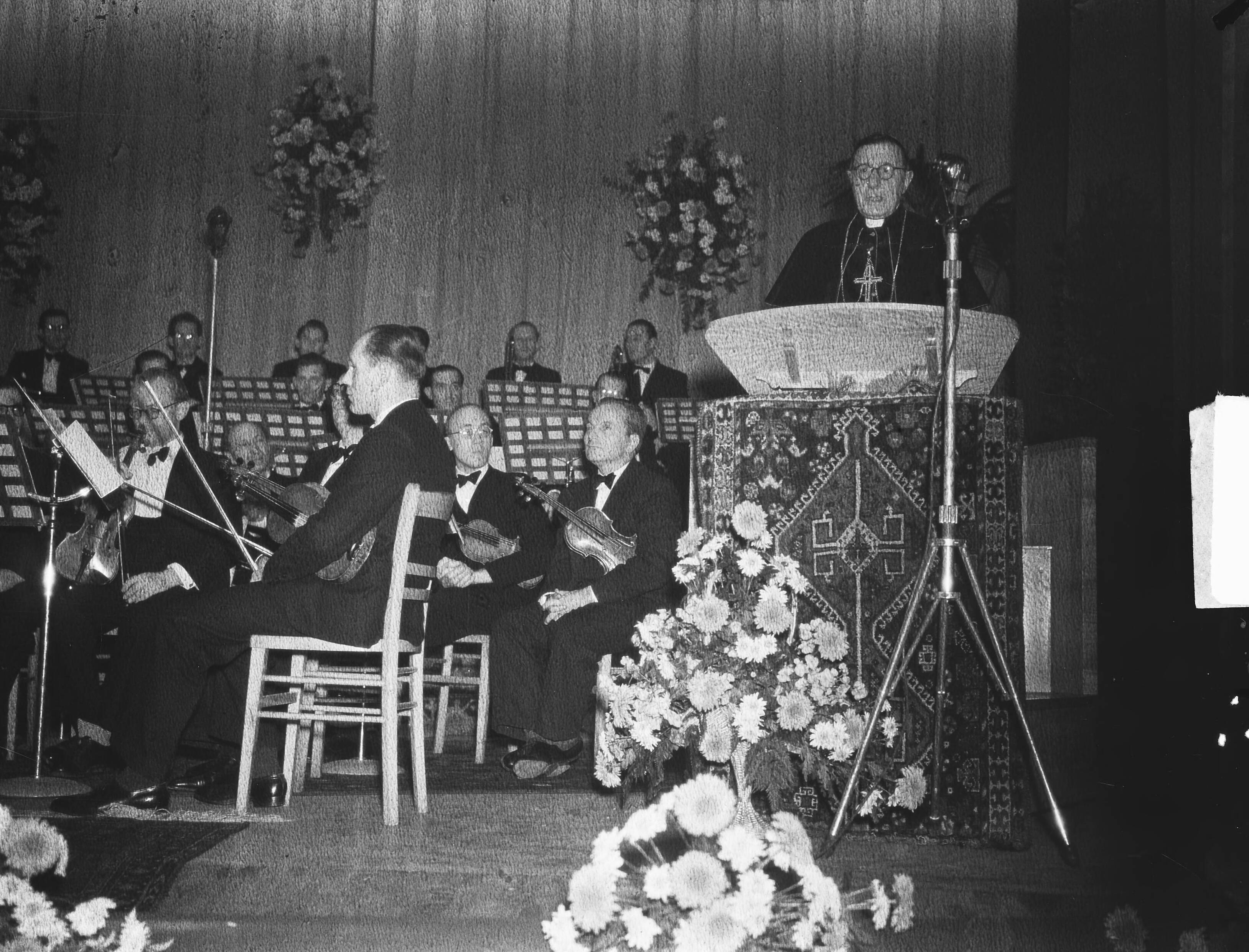 KRO 25-jarig jubileum — KRO 25-jarig jubileum. Toespraak van mgr. Huibers, bisschop van Haarlem. Op het podium het Symphonette-orkest onder leiding van Marinus van 't Woud — Foto: Bilsen, Joop van / Anefo. Licentie: Set B: Rechtenvrij / Publiek Domein. Bron: Nationaal Archief. http://hdl.handle.net/10648/a8e26386-d0b4-102d-bcf8-003048976d84