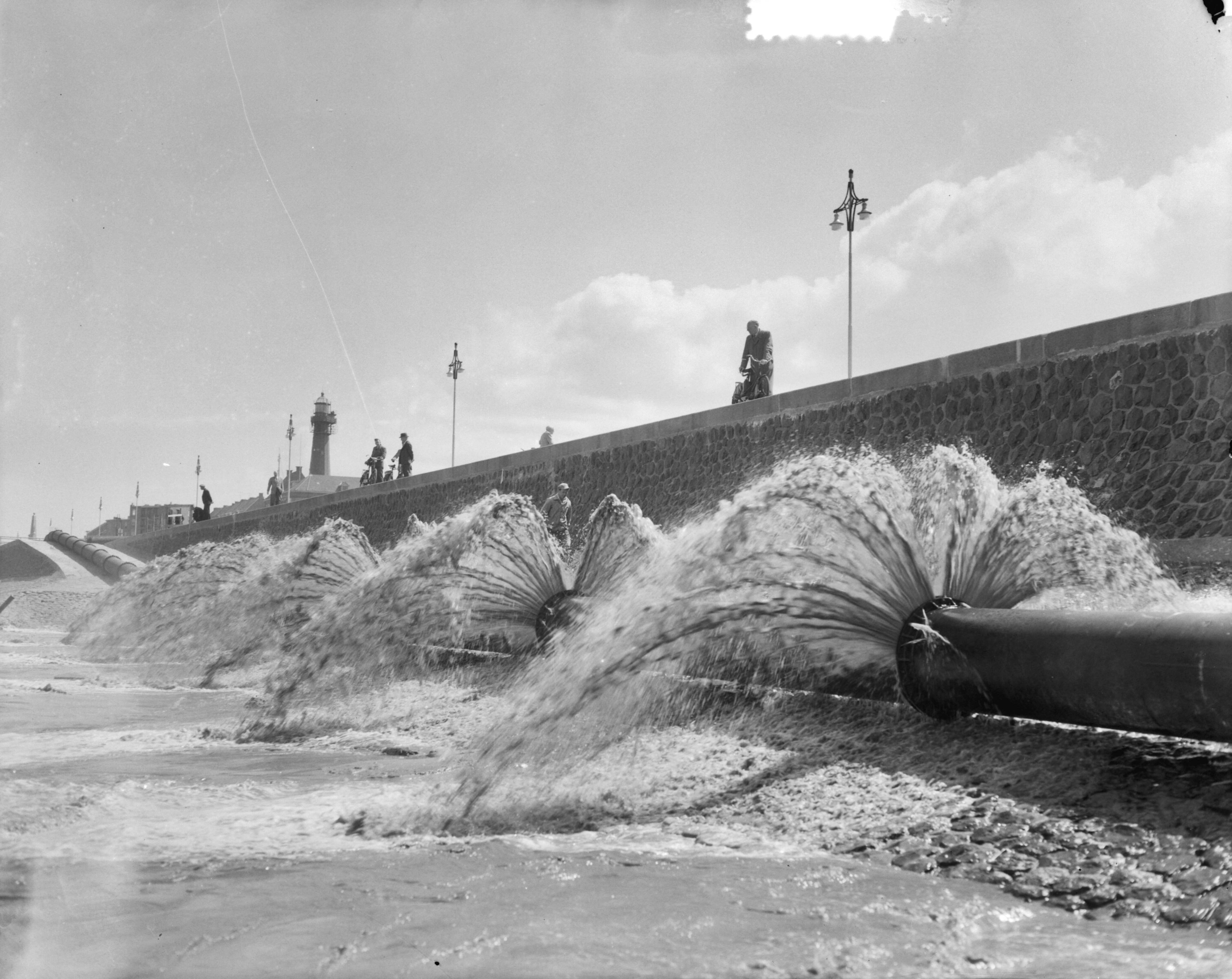 Fotocollectie Anefo — Spuitend zand vermengd met water op Scheveningse strand — Foto: Duinen, G.W. van / Anefo. Licentie: Set B: Rechtenvrij / Publiek Domein. Bron: Nationaal Archief. http://hdl.handle.net/10648/a90e10bc-d0b4-102d-bcf8-003048976d84