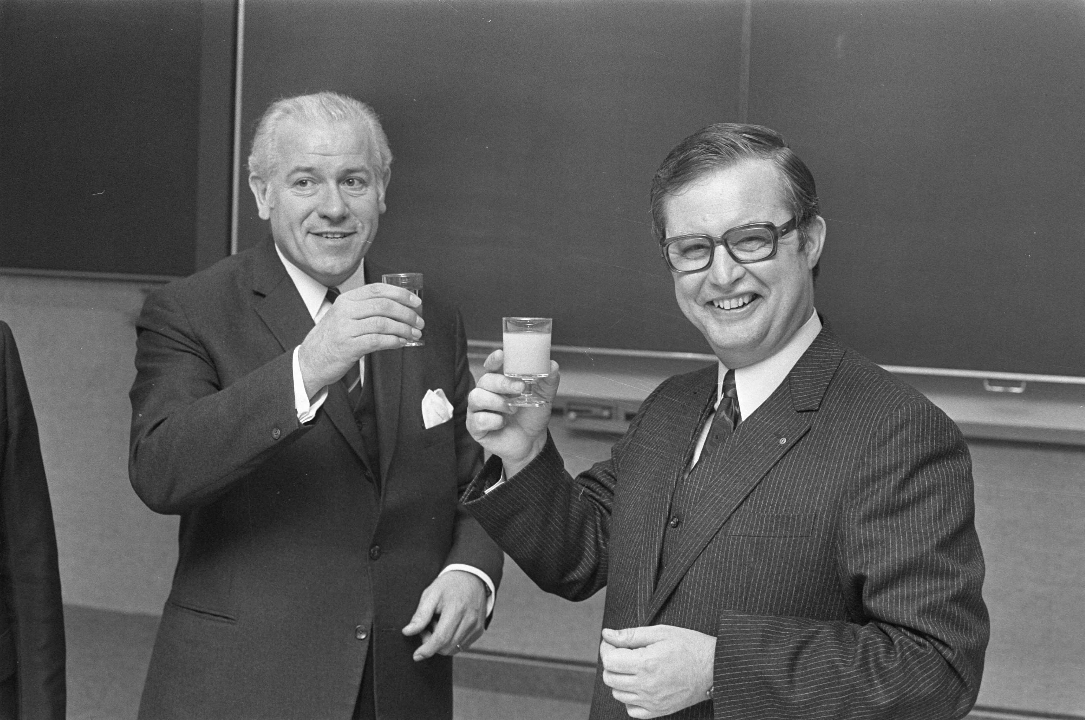 Fotocollectie Anefo — Persconferentie over fusie Albert Heijn en Simon de Wit in Zaandam; D.L. de Bruyn (links) en A. Heijn toosten — Foto: Verhoeff, Bert / Anefo. Licentie: Set B: Rechtenvrij / Publiek Domein. Bron: Nationaal Archief. http://hdl.handle.net/10648/abe1d56c-d0b4-102d-bcf8-003048976d84