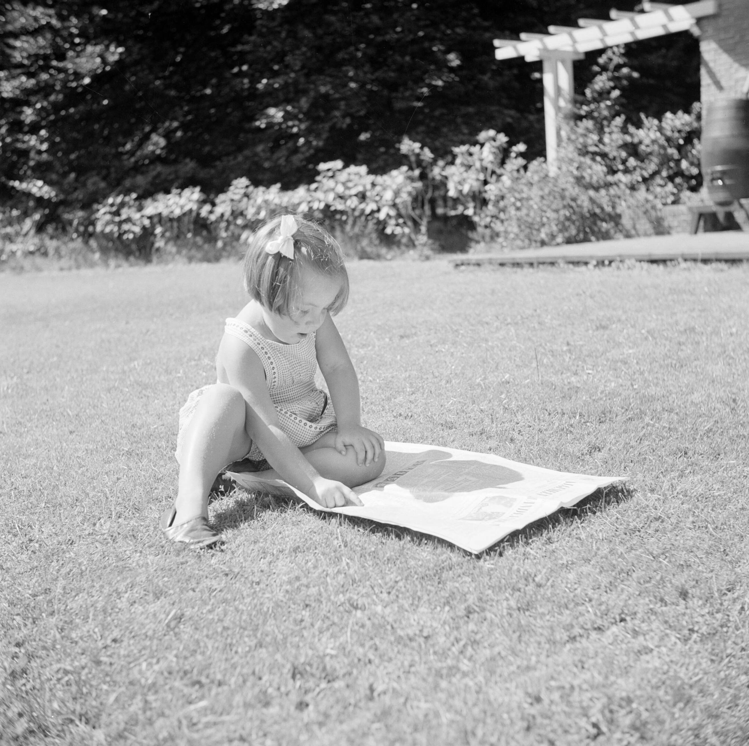 De koninklijke familie op paleis Soestdijk — Prinses Margriet speelt met een krant op het grasveld bij het zomerhuisje — Foto: Poll, Willem van de. Licentie: Set B: Rechtenvrij / Publiek Domein. Bron: Nationaal Archief. http://hdl.handle.net/10648/aee975d0-d0b4-102d-bcf8-003048976d84