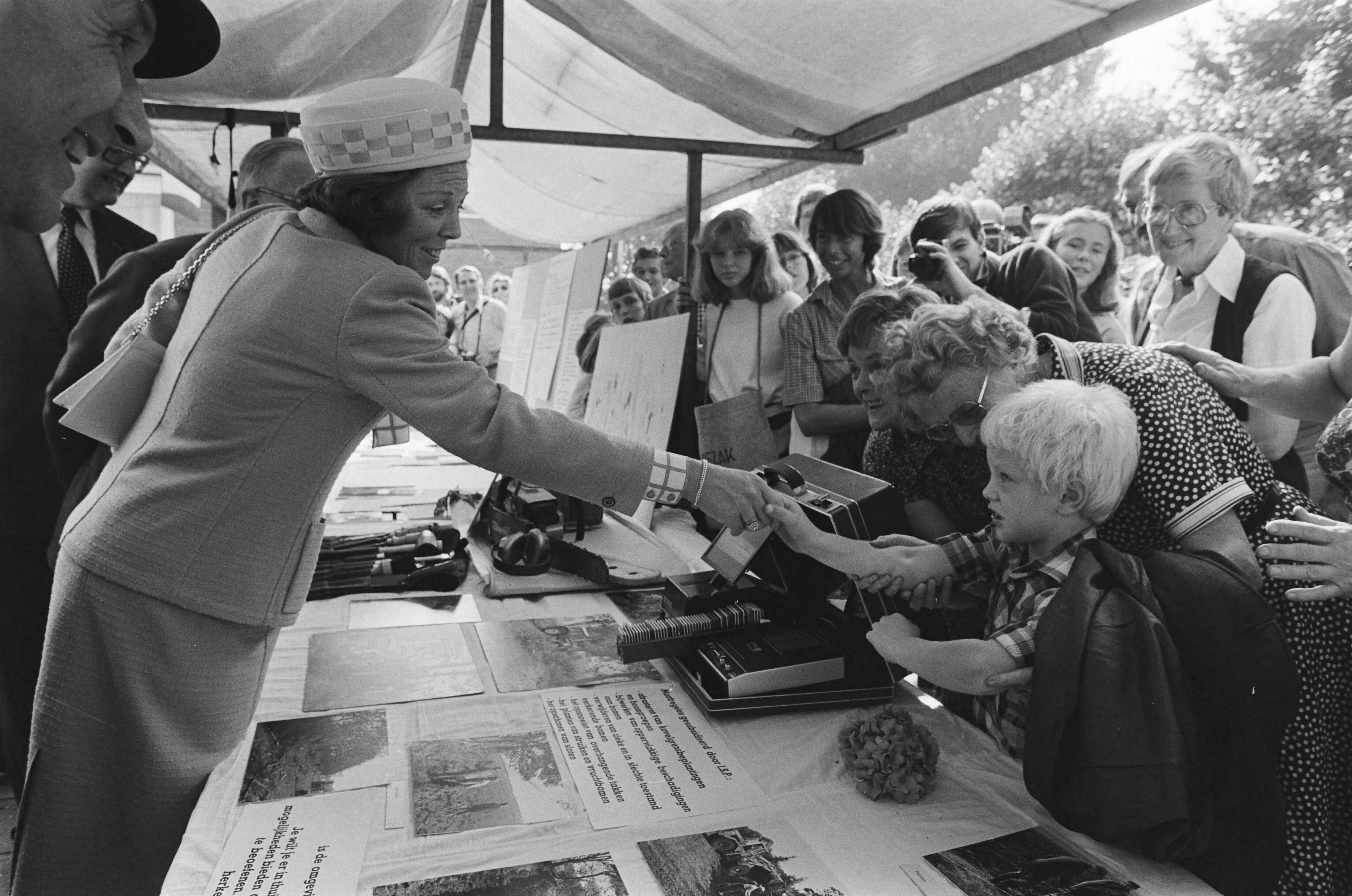 Viering 75-jarig bestaan van Ver. tot Behoud van Natuurmonumenten in Naarden, bijgewoond door koningin Beatrix en prins Claus — Beatrix troost 6-jarige Gertjan Boonstra, die een gedeelte van een stand op zijn hoofd kreeg — Foto: Dijk, Hans van / Anefo. Licentie: Set B: Rechtenvrij / Publiek Domein. Bron: Nationaal Archief. http://hdl.handle.net/10648/ace85512-d0b4-102d-bcf8-003048976d84