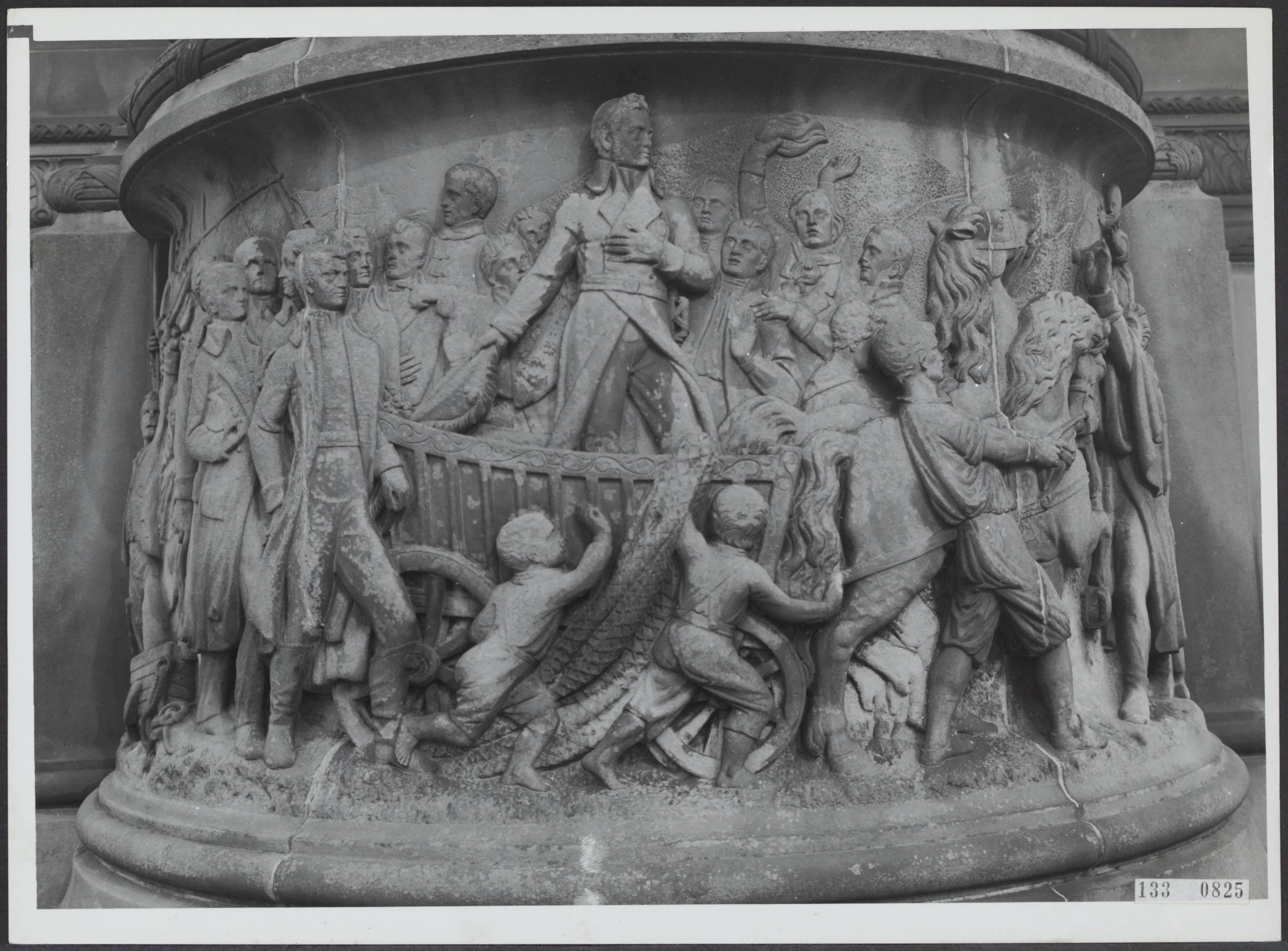 Fotocollectie Rijksvoorlichtingsdienst Eigen — Den Haag. Plein 1813: monument voor 50 jaar Nederlandse Onafhankelijkheid (1869) naar plannen van J. Ph. Koelman (sculptuur) en W.C. van der Waeyen Pieterszen (architectuur). Relief met de aankomst van de latere koning Willem I te Scheveningen — Foto: Fotodienst Gemeente Den Haag. Licentie: Set B: Rechtenvrij / Publiek Domein. Bron: Nationaal Archief. http://hdl.handle.net/10648/af5aa728-d0b4-102d-bcf8-003048976d84