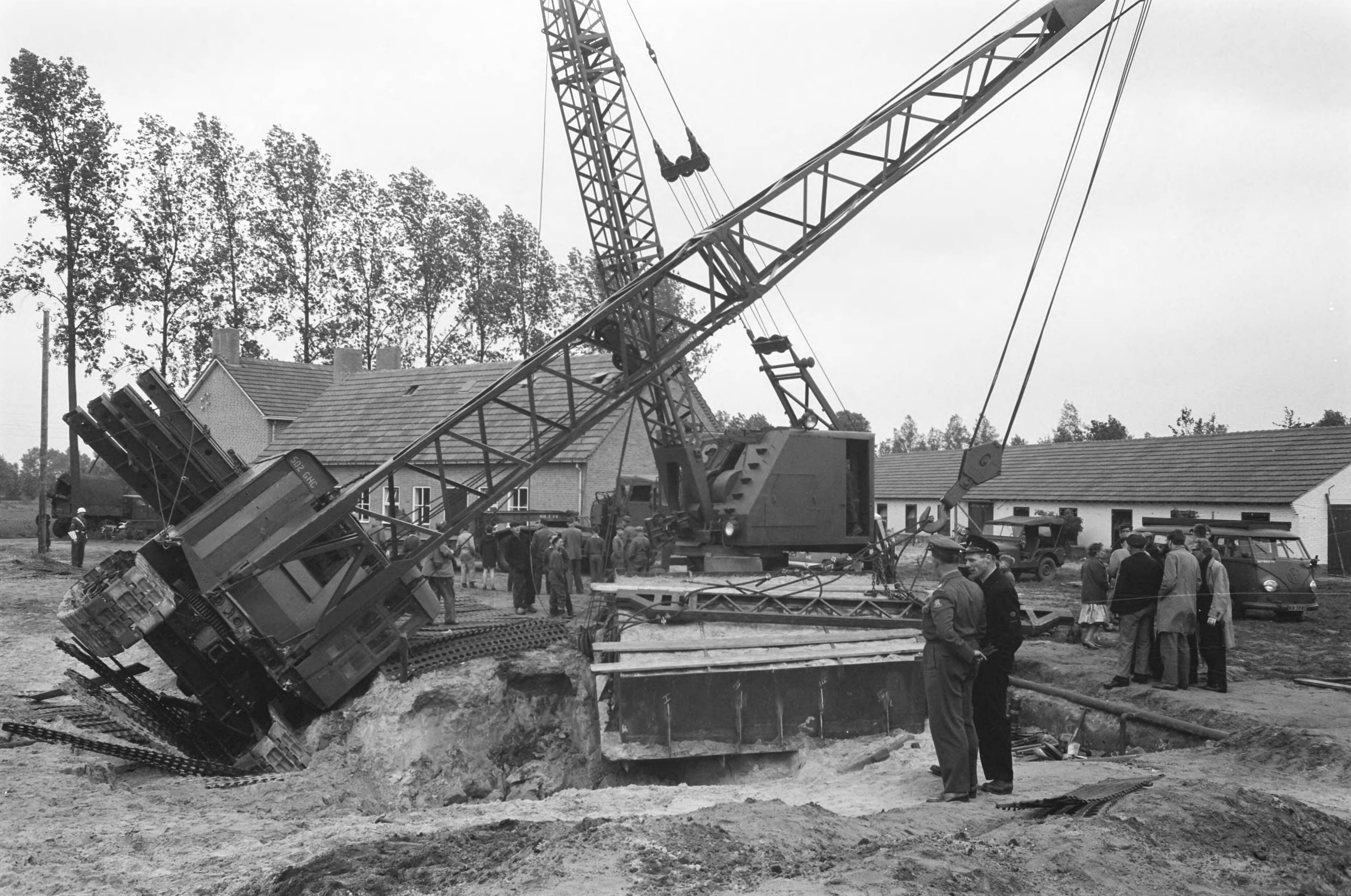 Fotocollectie Anefo — In Esch (N.B.) zijn militairen van het depot Genietroepen van de Koning Willem I-kazerne in Den Bosch bezig geweest met het uitgraven van een Romeins graf uit het begin van onze jaartelling. Het graf werd in een metalen bekisting gebouwd om in zijn geheel naar Amersfoort te worden overgebracht, waar de Rijksdienst voor Oudheidkundig Bodemonderzoek het zal bestuderen. Gisteren wilden twee kranen het graf op een vrachtauto tillen; een van de kranen kantelde echter. Het graf bleef ongedeerd — Foto: Pot, Harry / Anefo. Licentie: Set B: Rechtenvrij / Publiek Domein. Bron: Nationaal Archief. http://hdl.handle.net/10648/a9d666d4-d0b4-102d-bcf8-003048976d84