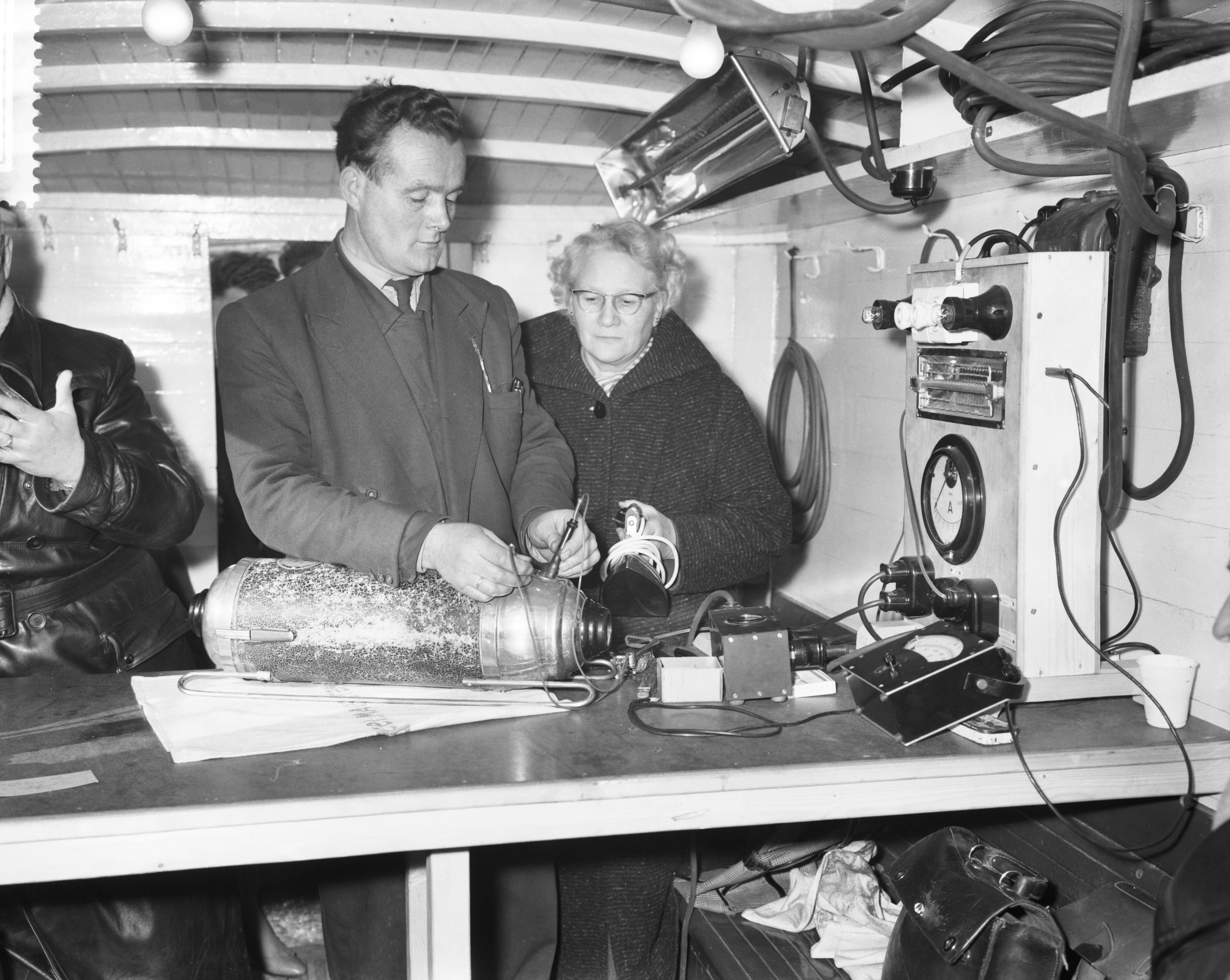 Fotocollectie Anefo — Doormeten van elektrische apparaten door het GEB in Tuindorp Oostzaan — Foto: Rossem, Wim van / Anefo. Licentie: Set B: Rechtenvrij / Publiek Domein. Bron: Nationaal Archief. http://hdl.handle.net/10648/a9a7bd5c-d0b4-102d-bcf8-003048976d84