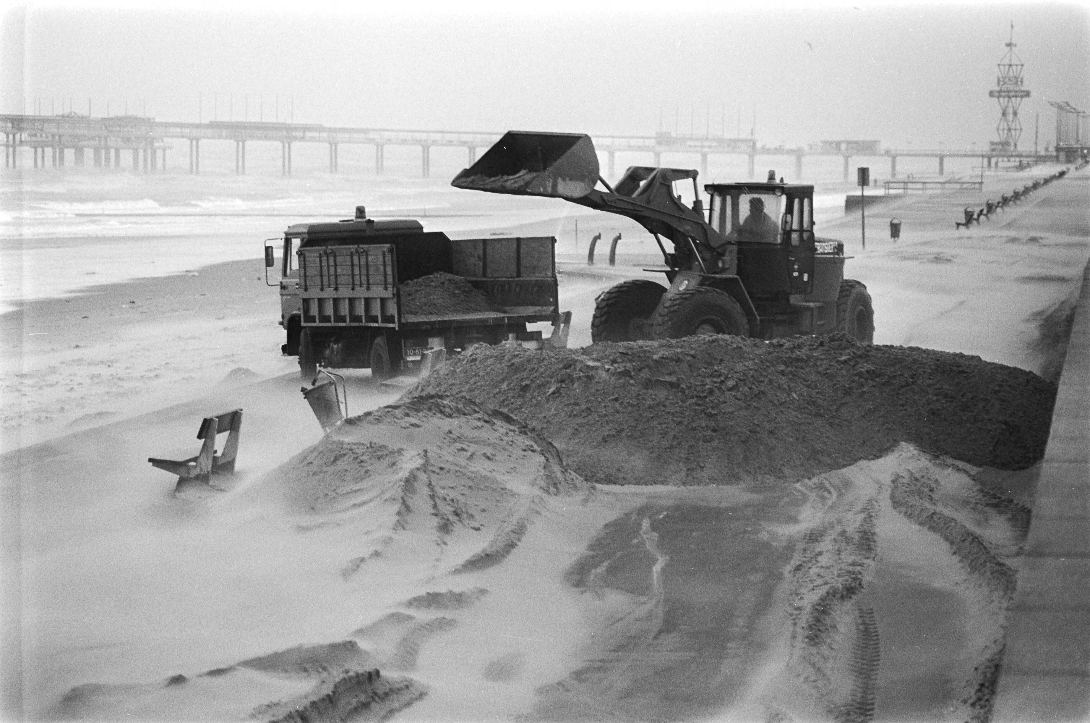 Fotocollectie Anefo — Bulldozer ruimt opgewaaid zand in Scheveningen op — Foto: Suyk, Koen / Anefo. Licentie: Set B: Rechtenvrij / Publiek Domein. Bron: Nationaal Archief. http://hdl.handle.net/10648/acaa05c8-d0b4-102d-bcf8-003048976d84