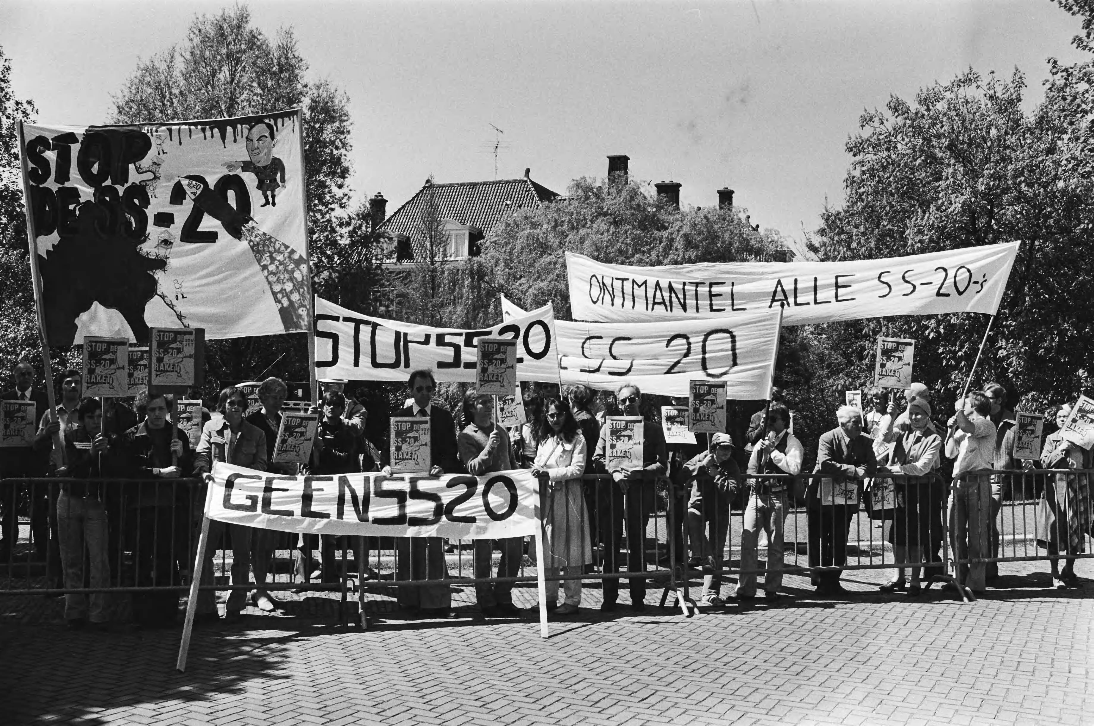 Demonstratie voor de Russische Ambassade in Den Haag tegen de fabrikage van de SS 20 raket — Demonstratie met spandoeken waarop o.a. de tekst "Ontmantel alle SS-20" en "Geen SS-20" — Foto: Suyk, Koen / Anefo. Licentie: Set B: Rechtenvrij / Publiek Domein. Bron: Nationaal Archief. http://hdl.handle.net/10648/acca6dae-d0b4-102d-bcf8-003048976d84