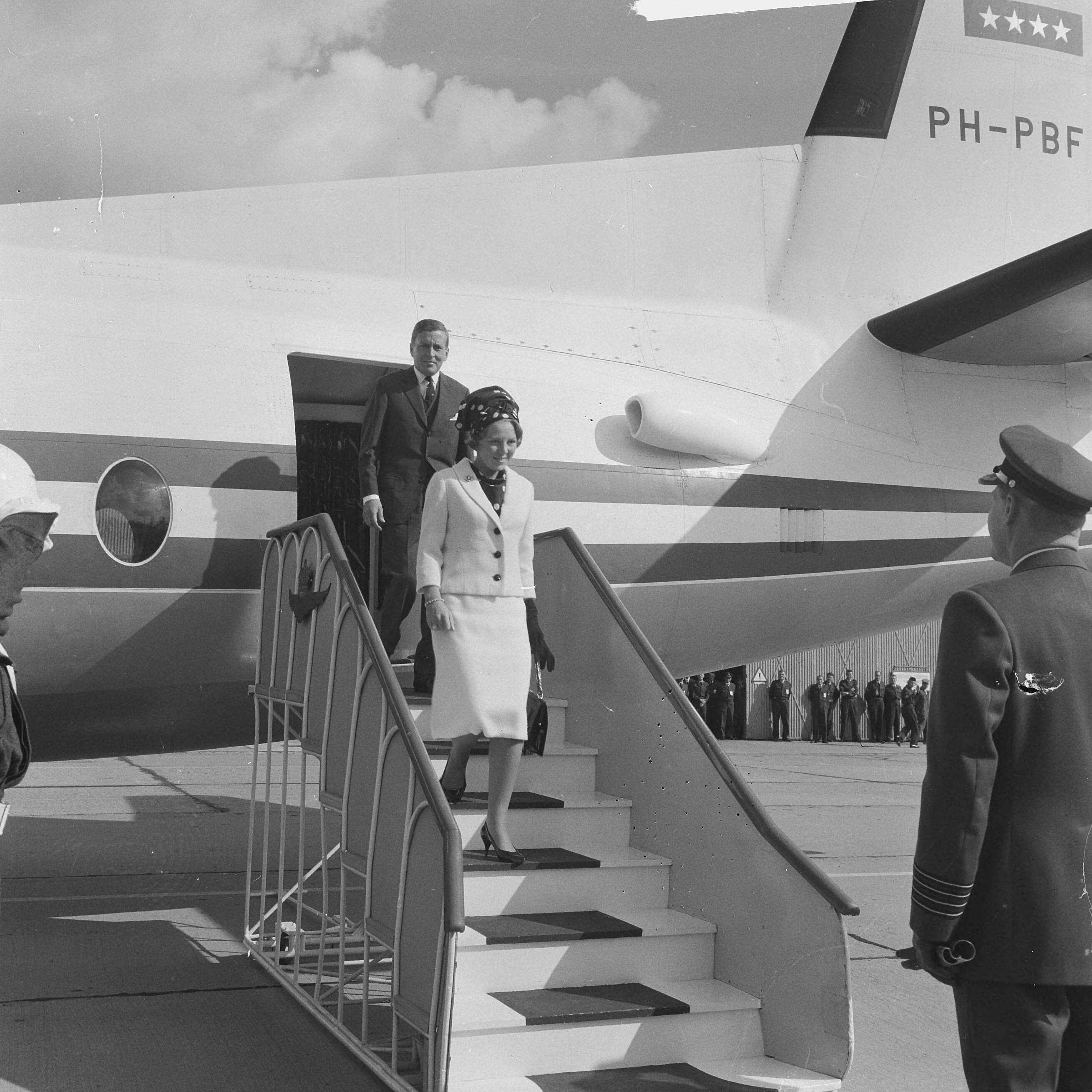 Bezoek van prinses Beatrix en Claus von Amsberg aan de drie noordelijke provincies — Bezoek prinses Beatrix en haar verloofde Claus von Amsberg aan Leeuwarden, aankomst op vliegbasis Leeuwarden met de Fokker Friendship "Gerben Wagenaar". Het paar op de vliegtuigtrap met rechts de commandant van de vliegbasis, kolonel J.H. Knoop — Foto: Kroon, Ron / Anefo. Licentie: Set B: Rechtenvrij / Publiek Domein. Bron: Nationaal Archief. http://hdl.handle.net/10648/aabefbba-d0b4-102d-bcf8-003048976d84