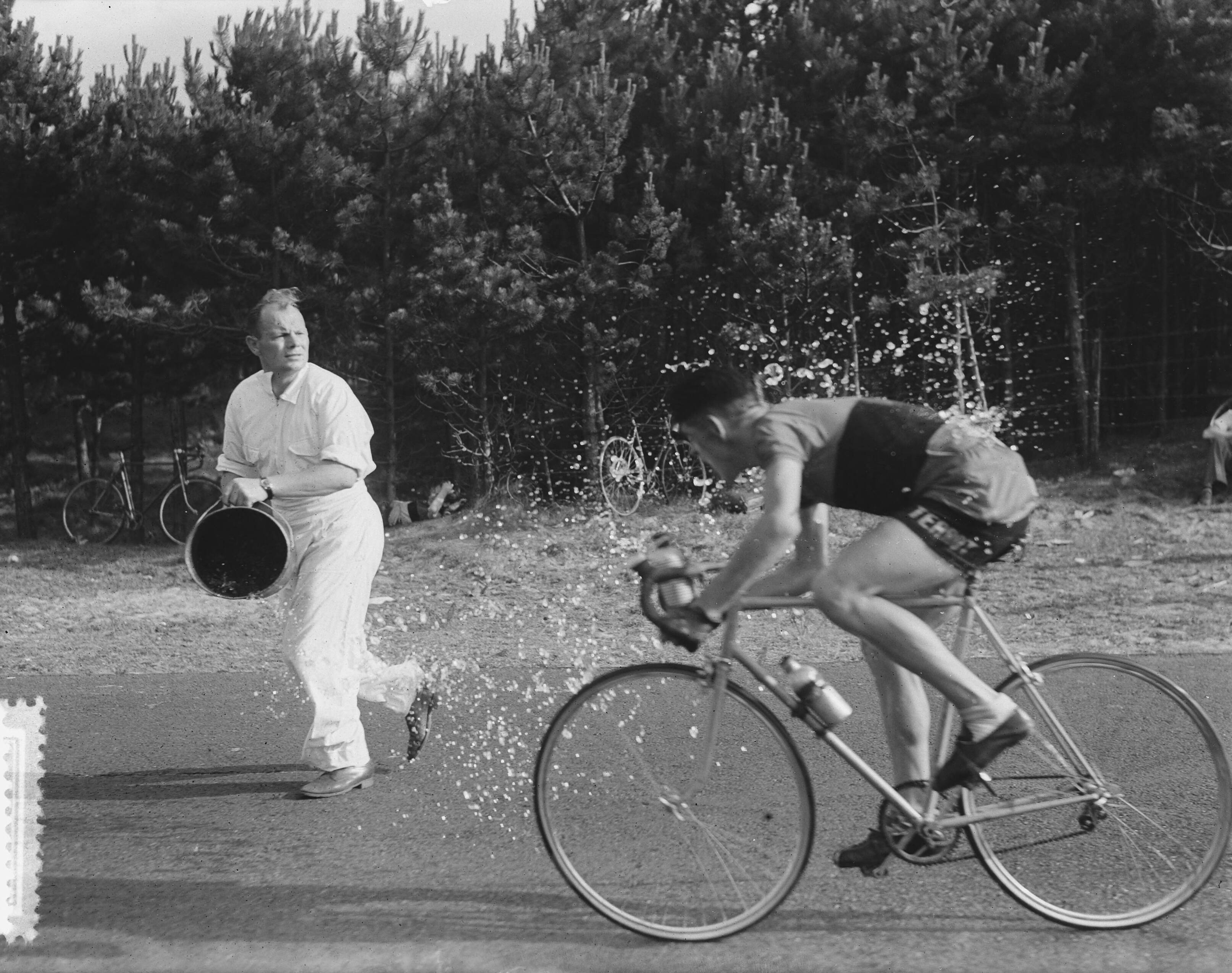 Nederlandse kampioenschap wegwedstrijd wielrennen voor amateurs (1952) — Nederlands kampioenschap wielrennen op de weg voor amateurs op het circuit van Zandvoort. De latere winnaar Cees Aanraad uit Oud-Gastel krijgt een emmer water over zicht heen — Foto: Noske, J.D. / Anefo. Licentie: Set B: Rechtenvrij / Publiek Domein. Bron: Nationaal Archief. http://hdl.handle.net/10648/a8fc9972-d0b4-102d-bcf8-003048976d84