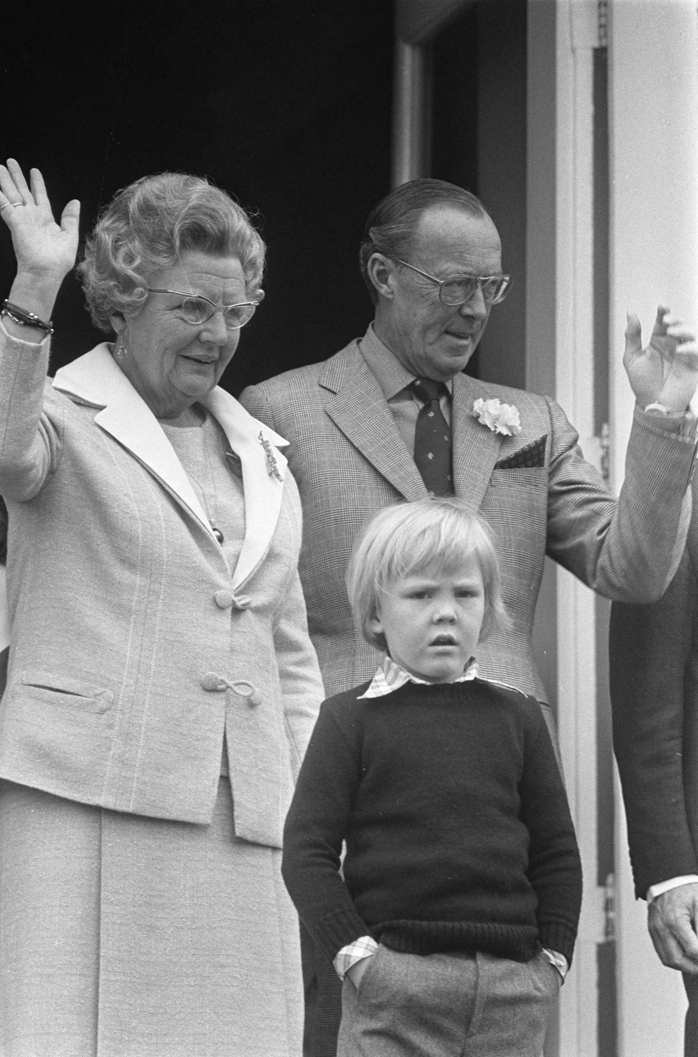 Koninginnedag 1973 — Het defilé op Soestdijk, koningin Juliana en prins Bernhard zwaaien, prins Willem-Alexander staat met zijn handen in zijn zakken — Foto: Fotograaf Onbekend / Anefo. Licentie: Set B: Rechtenvrij / Publiek Domein. Bron: Nationaal Archief. http://hdl.handle.net/10648/ac2aff30-d0b4-102d-bcf8-003048976d84