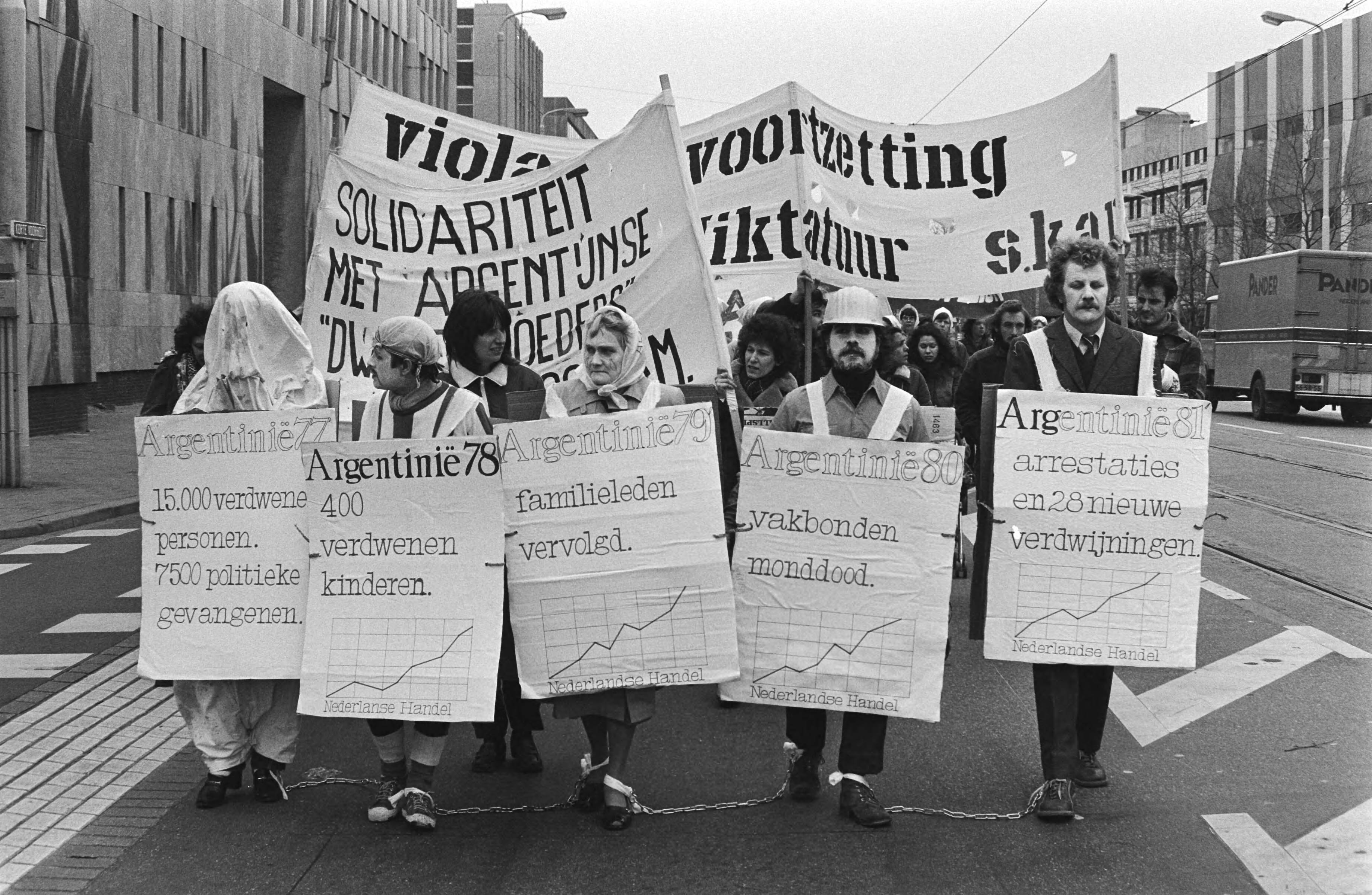 Fotocollectie Anefo — Demonstratie in Den Haag tegen dictatuur in Argentinie, met kettingen aan elkaar gebonden proberen demonstranten dictatuur in Argentinie uit te beelden — Foto: Dijk, Hans van / Anefo. Licentie: Set B: Rechtenvrij / Publiek Domein. Bron: Nationaal Archief. http://hdl.handle.net/10648/acf7da78-d0b4-102d-bcf8-003048976d84