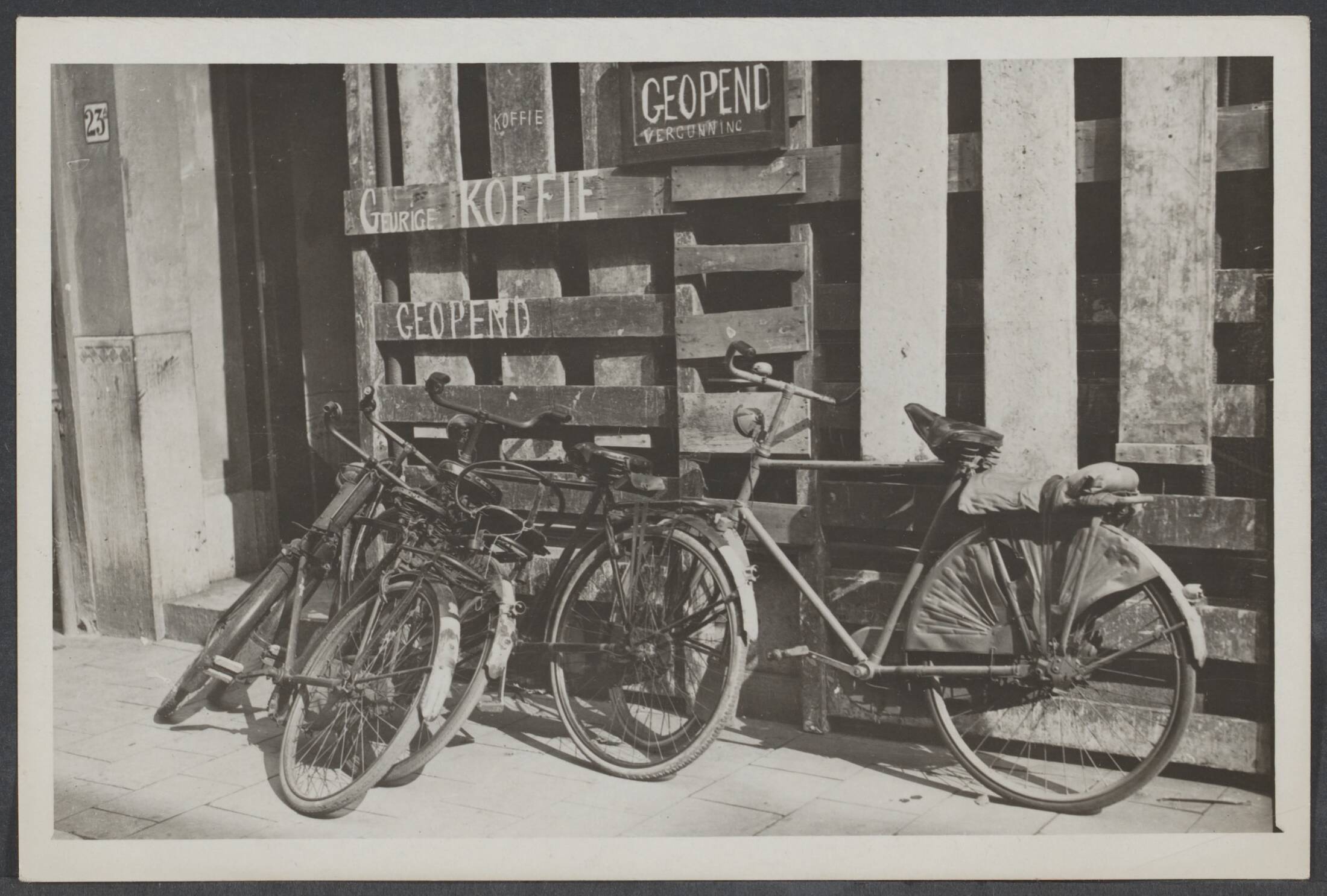 Vervoer — Den Haag. Van den nood een deugd gemaakt. ook in Den haag gaat het gewone leven weer zijn gang. Al is het exterieur vernield, binnen kan men toch van z'n kopje koffie genieten — Foto: N.V. Vereenigde Fotobureaux. Licentie: Set B: Rechtenvrij / Publiek Domein. Bron: Nationaal Archief. http://hdl.handle.net/10648/49d78884-8077-edf1-6f37-85ac3009743a