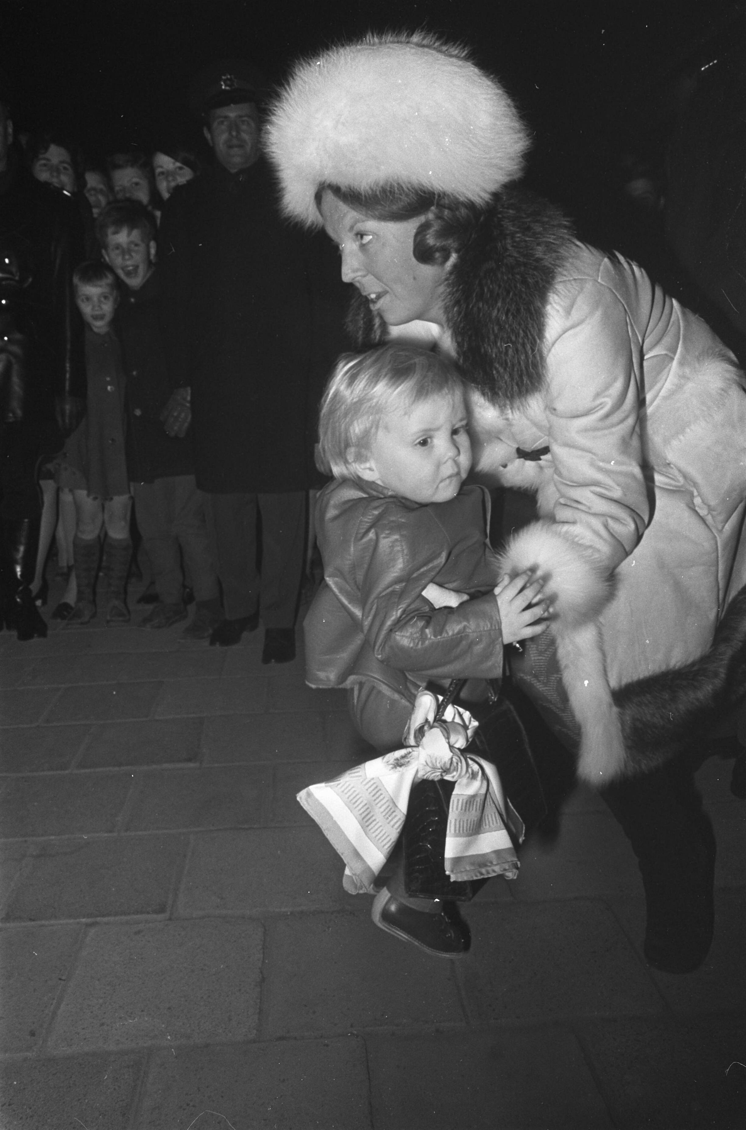 Fotocollectie Anefo — Koninklijke Familie vertrekt per trein station Baarn naar Lech (Oostenrijk) voor wintersportvakantie, Prinses Beatrix tilt Prins Willem Alexander op — Foto: Nijs, Jac. de / Anefo. Licentie: Set B: Rechtenvrij / Publiek Domein. Bron: Nationaal Archief. http://hdl.handle.net/10648/ab614eba-d0b4-102d-bcf8-003048976d84