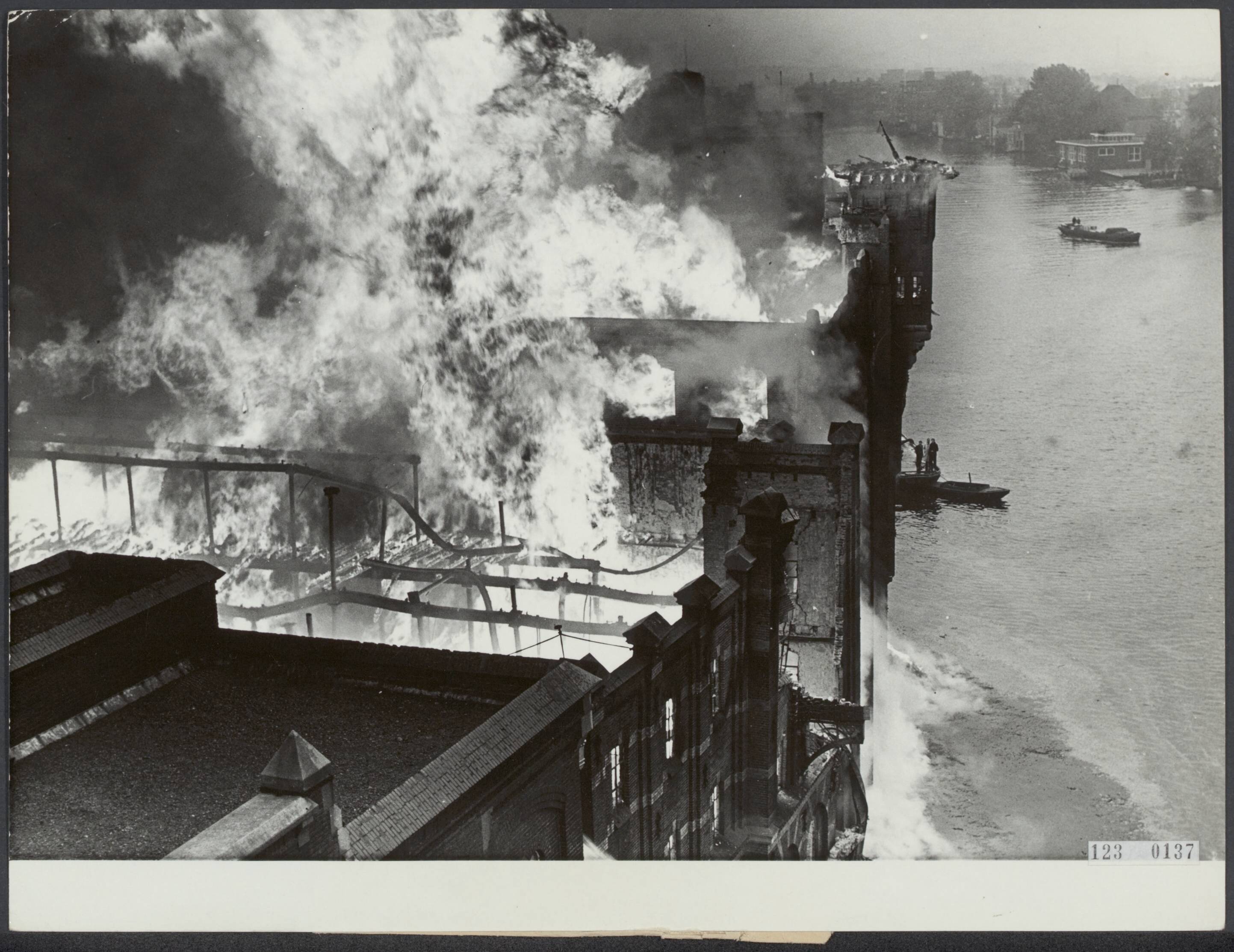 Fotocollectie Rijksvoorlichtingsdienst Eigen — Vrijdagmorgen vroeg is een enorme brand uitgebroken in Zaandam waarbij een serie pakhuizen volkomen in de as zijn gelegd. Het brandende complex — Foto: ANP / RVD of rechtenvrij. Licentie: Set B: Rechtenvrij / Publiek Domein. Bron: Nationaal Archief. http://hdl.handle.net/10648/af2d01e2-d0b4-102d-bcf8-003048976d84