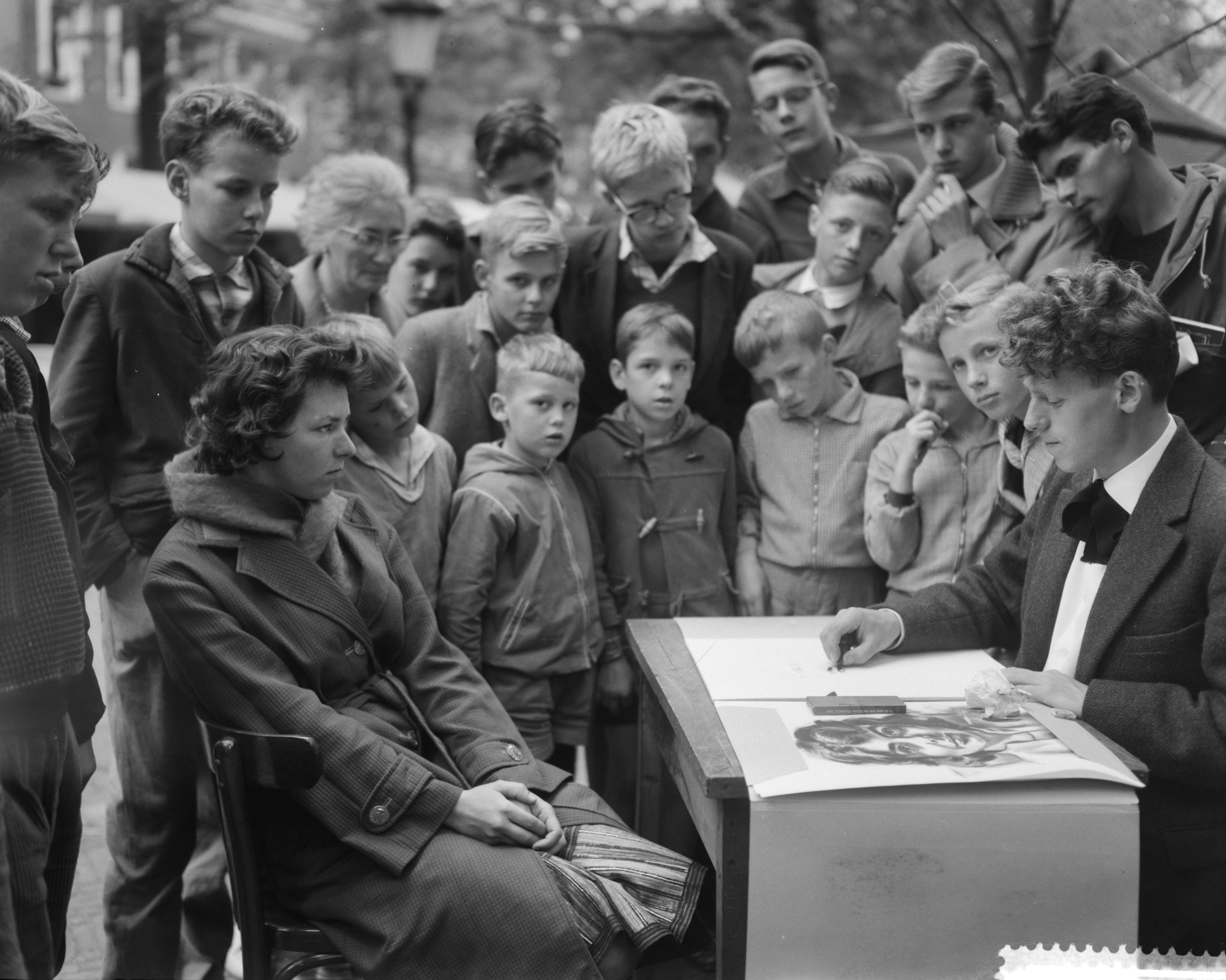 Fotocollectie Anefo — Kunstenaarsmanifestatie op het Janskerkhof te Utrecht. Een tekenaar bezig met het maken van een portret — Foto: Bilsen, Joop van / Anefo. Licentie: Set B: Rechtenvrij / Publiek Domein. Bron: Nationaal Archief. http://hdl.handle.net/10648/a9b8cb92-d0b4-102d-bcf8-003048976d84