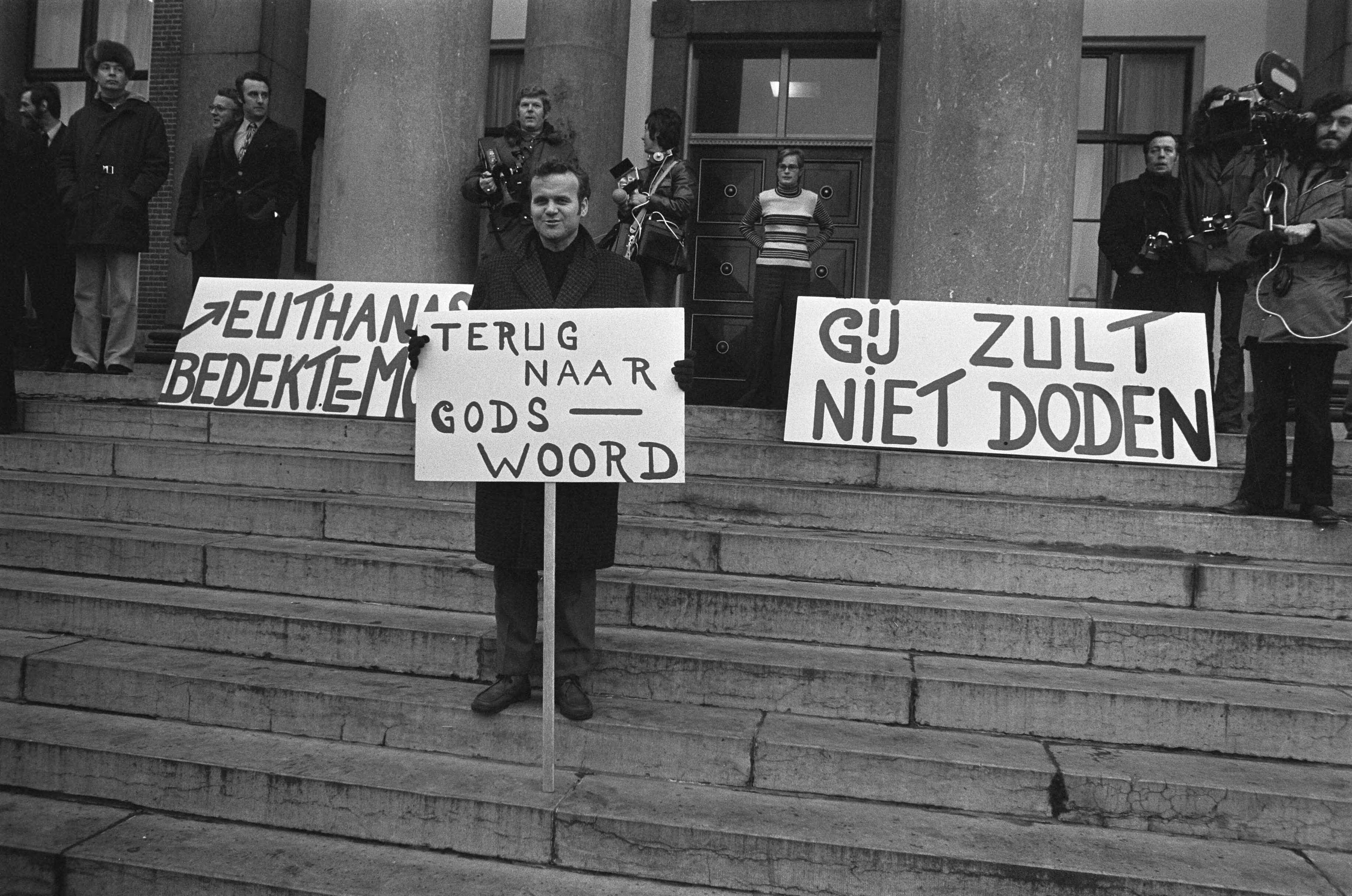 Fotocollectie Anefo — Euthanasie-proces begonnen tegen mevrouw Postma van Boven in Leeuwarden, demonstranten met protestborden — Foto: Verhoeff, Bert / Anefo. Licentie: Set B: Rechtenvrij / Publiek Domein. Bron: Nationaal Archief. http://hdl.handle.net/10648/ac247372-d0b4-102d-bcf8-003048976d84